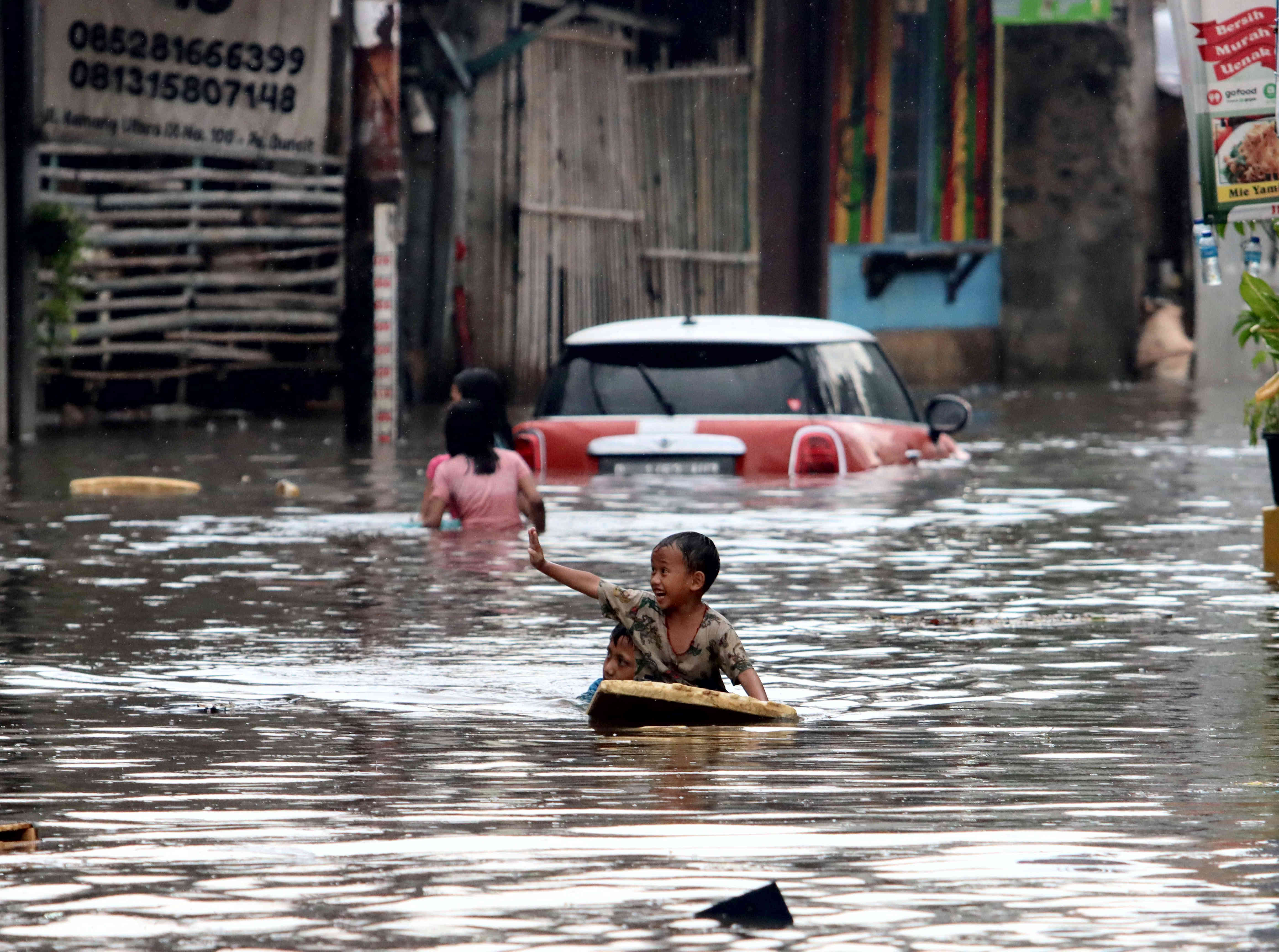 Anak-anak bermain air dekat kendaraan yang terjebak banjir di kawasan Kemang, Jakarta, Sabtu (5/11/2022).