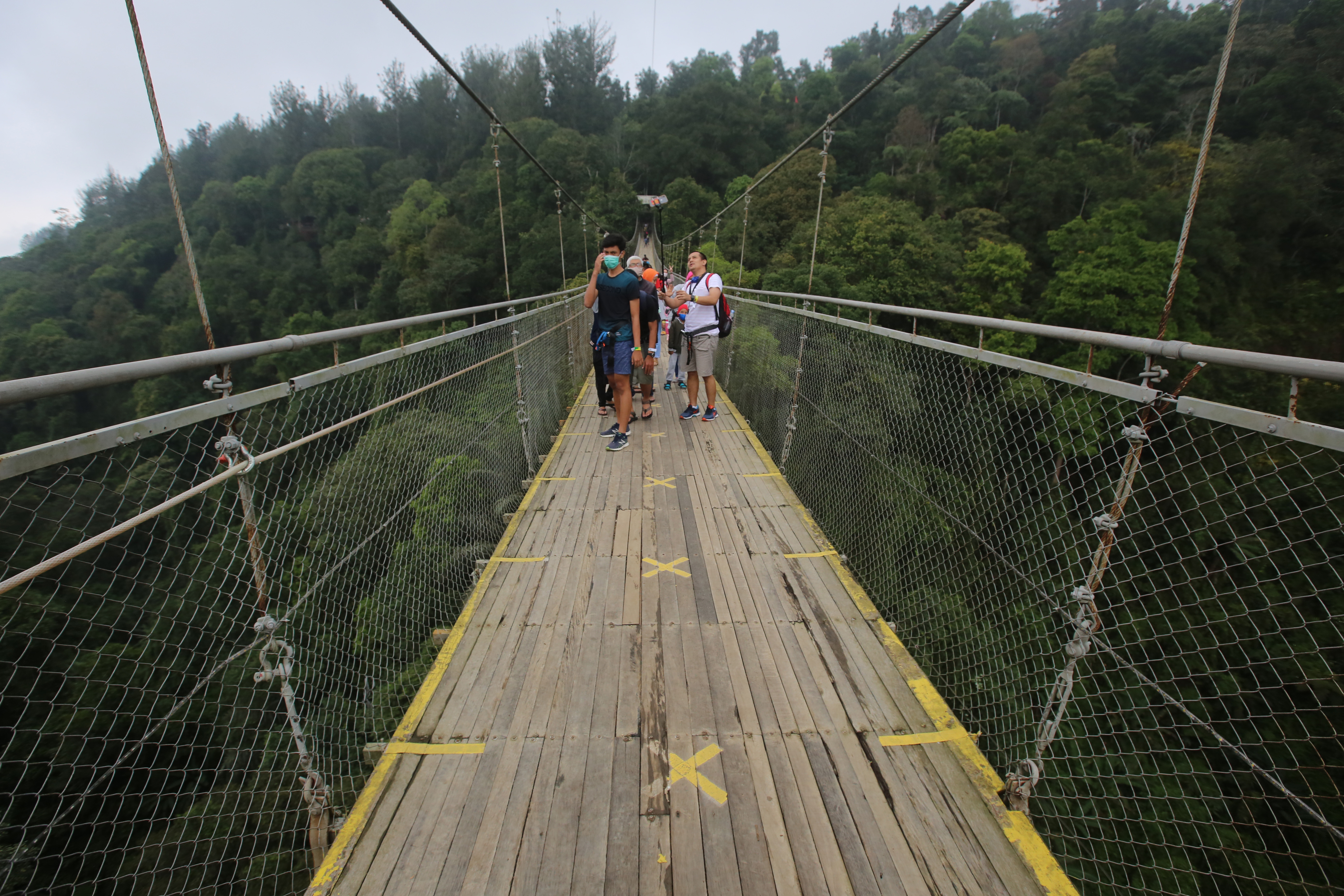 Pengunjung berfoto saat melewati jembatan gantung di kawasan Taman Nasional Gunung Gede Pangrango Kabupaten Sukabumi, Jawa Barat.