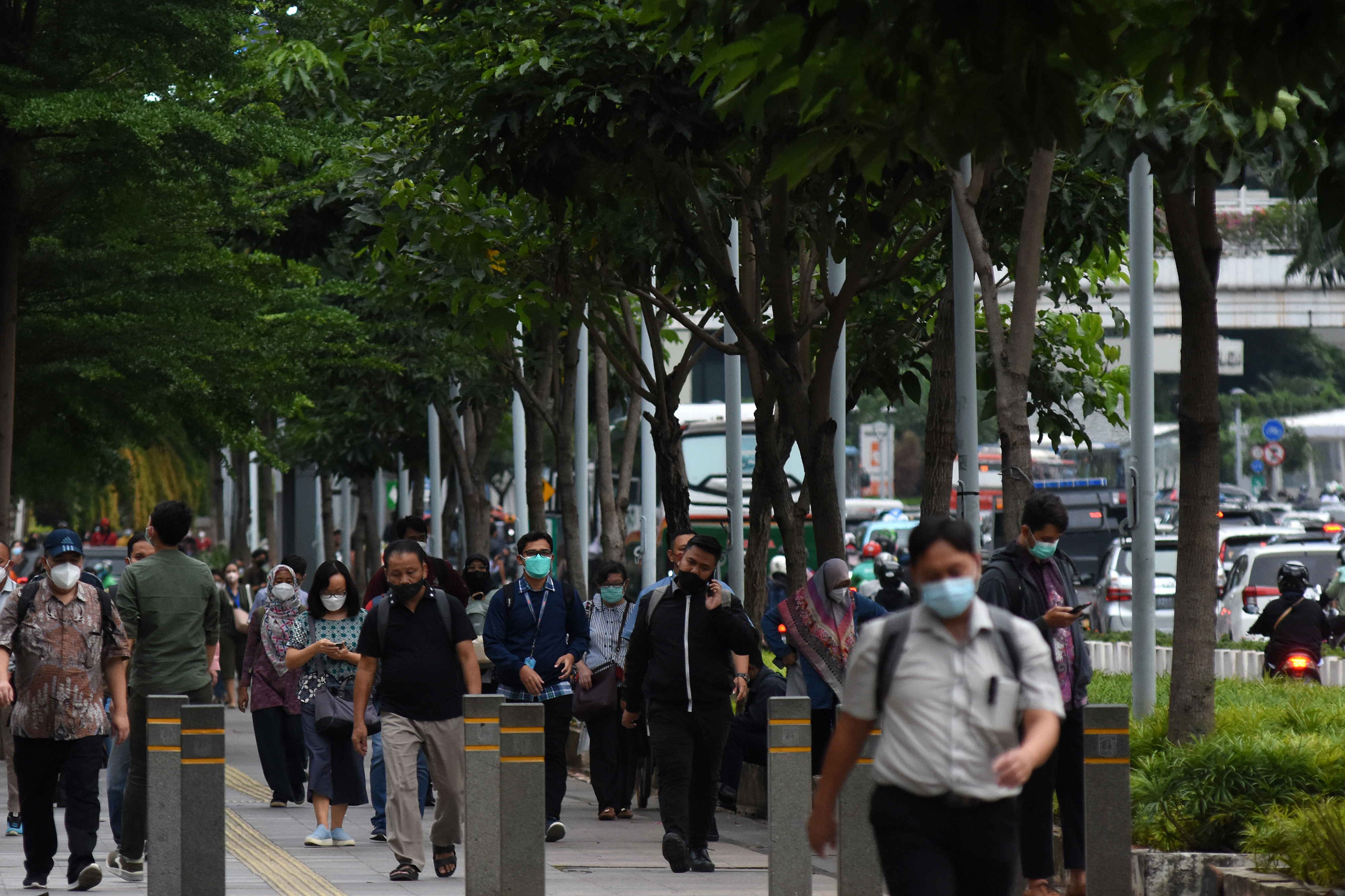 Pekerja berjalan di trotoar kawasan Sudirman, Jakarta.