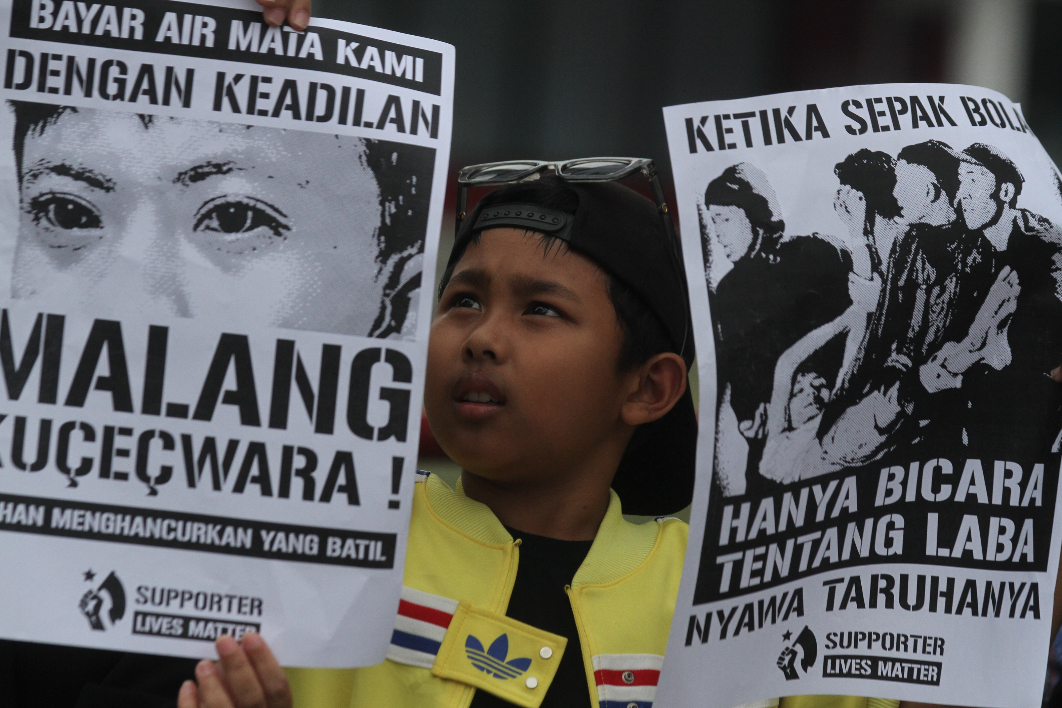 Suporter Arema FC (Aremania) membawa poster berisi protes untuk mengusut tuntas tragedi kanjuruhan