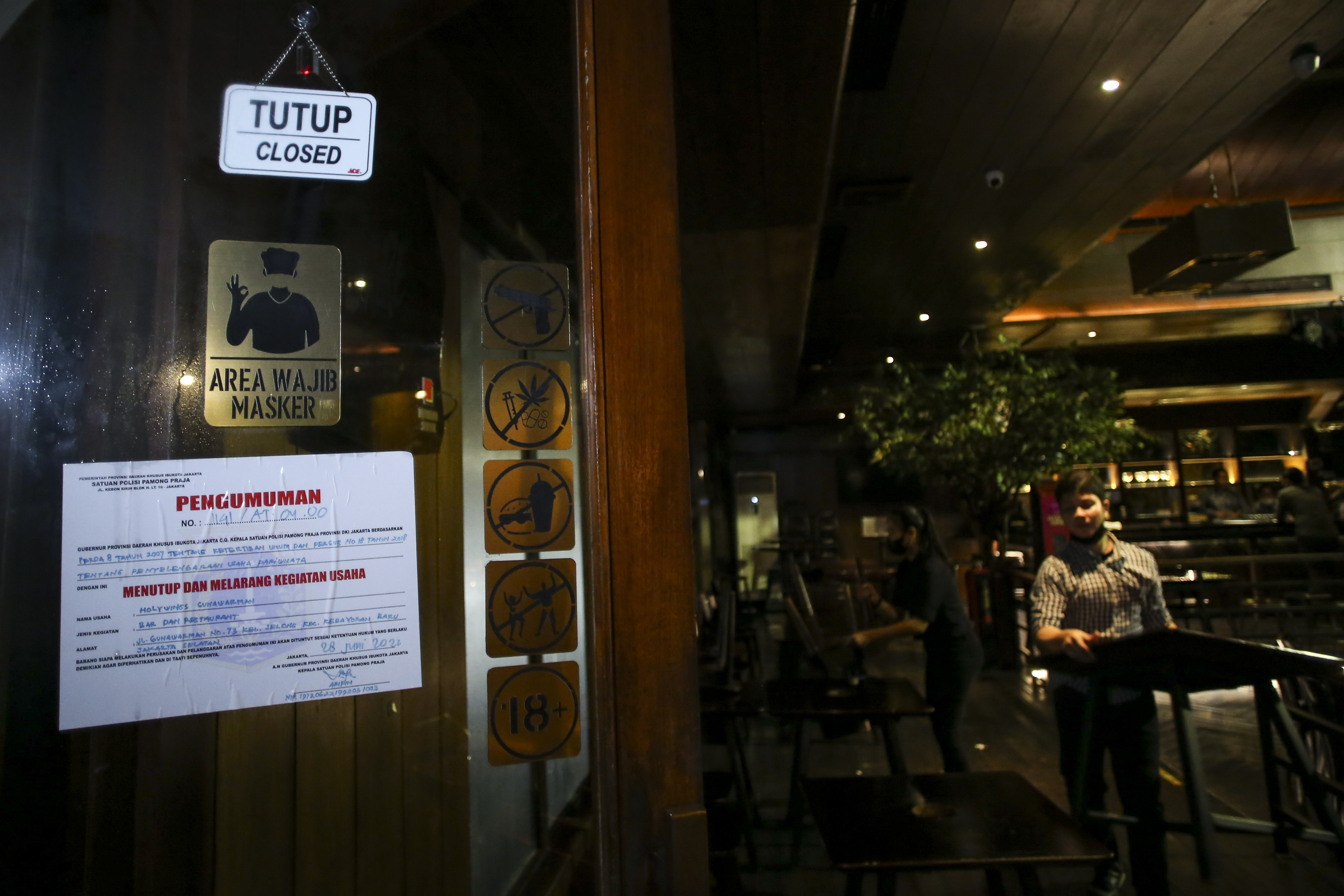 Ilustrasi--Pekerja merapihkan kursi di gerai Holywings yang tutup di kawasan Gunawarman, Jakarta.