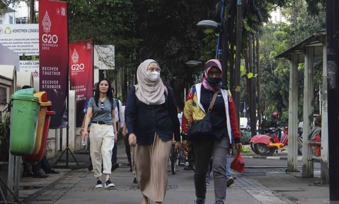Warga Jakarta sedang berjalan sembari memakai masker