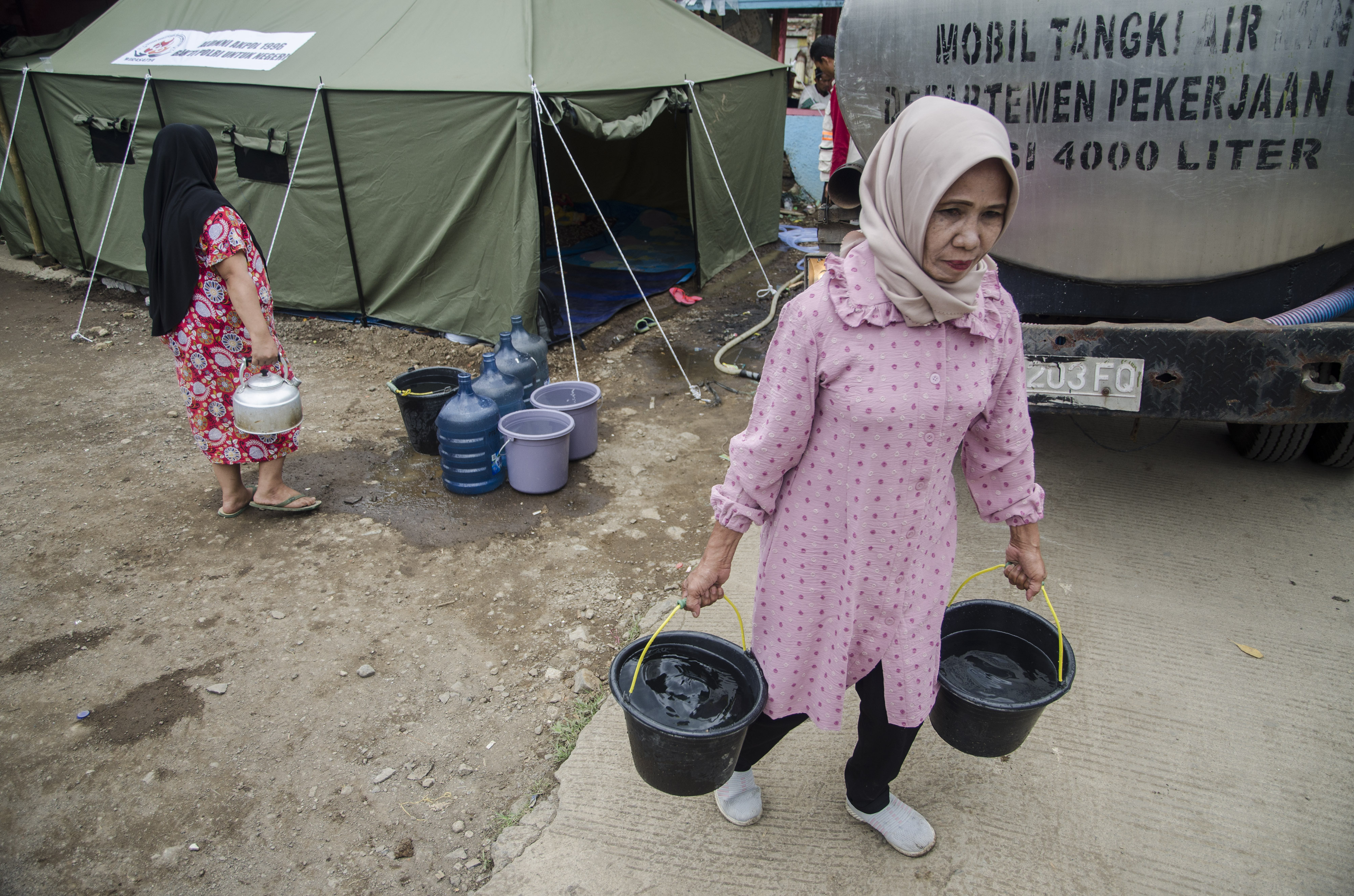 Warga terdampak gempa di Cianjur, Jawa Barat, membawa pasokan air bersih.