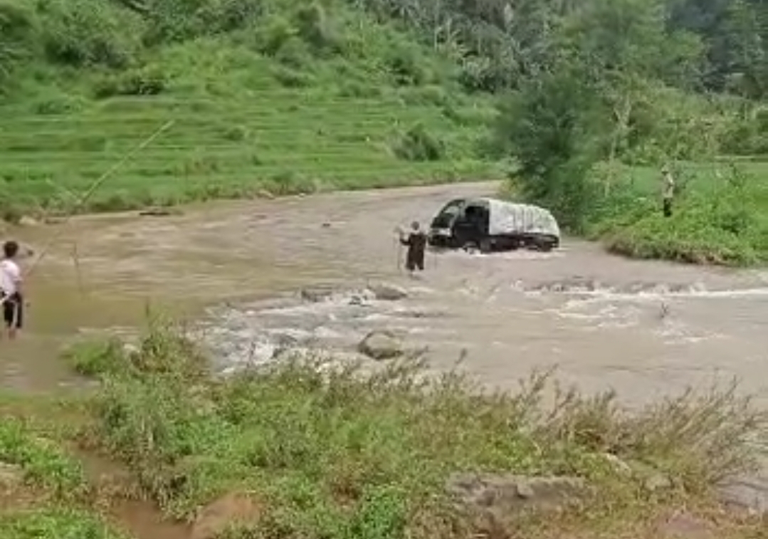 Sebuah mobil berupaya melintasi sungai yang berarus deras di  Desa Sukamulya, Kecamatan Naringgul, Kabupaten Cianjur, Jawa Barat, 