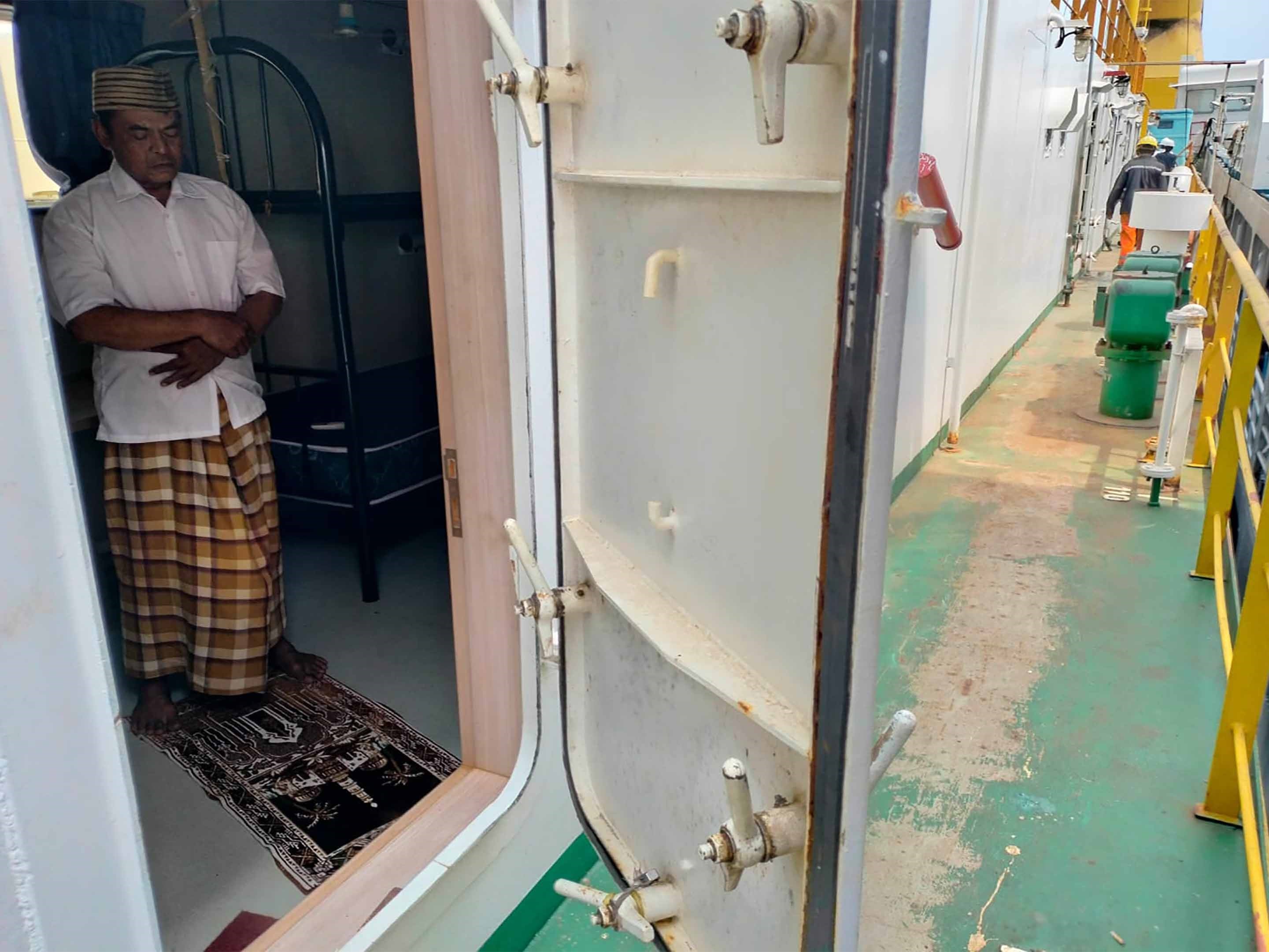Pekerja menunaikan salat di atas dek kapal. 