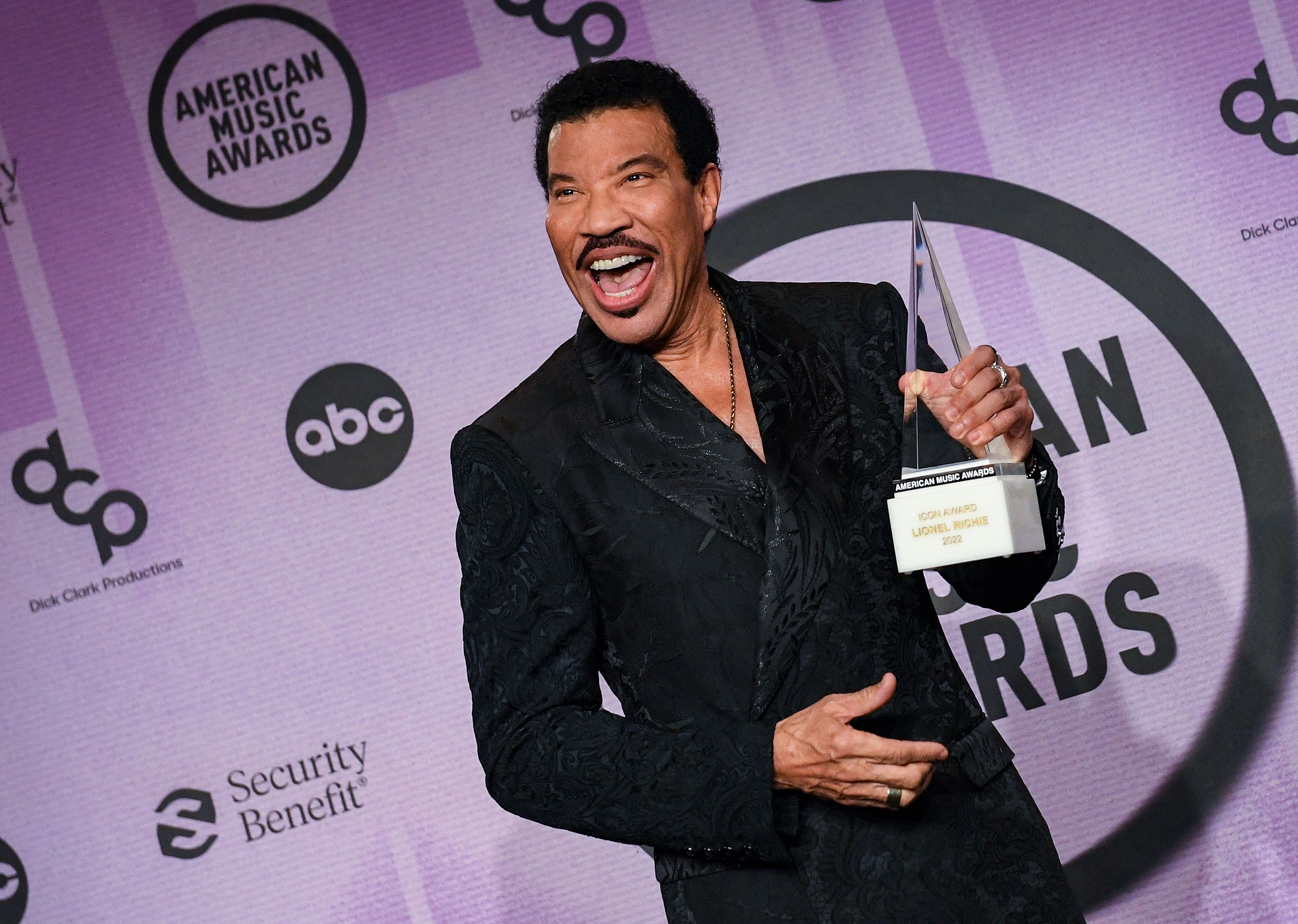 Penyanyi legendaris Lionel Richie memamerkan trofi American Music Awards yang dimenangkannya.