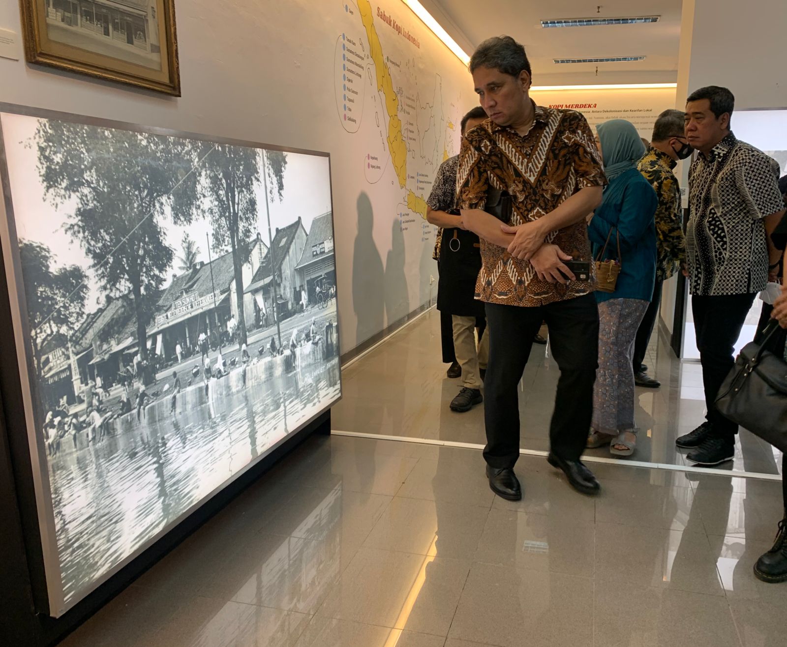 Dirjen Kemendikbudristek Hilmar Farid mengamati foto arsip cikal bakal kedai Bakoel Koffie di pameran Kopi Togetherness, Museum Nasional. 