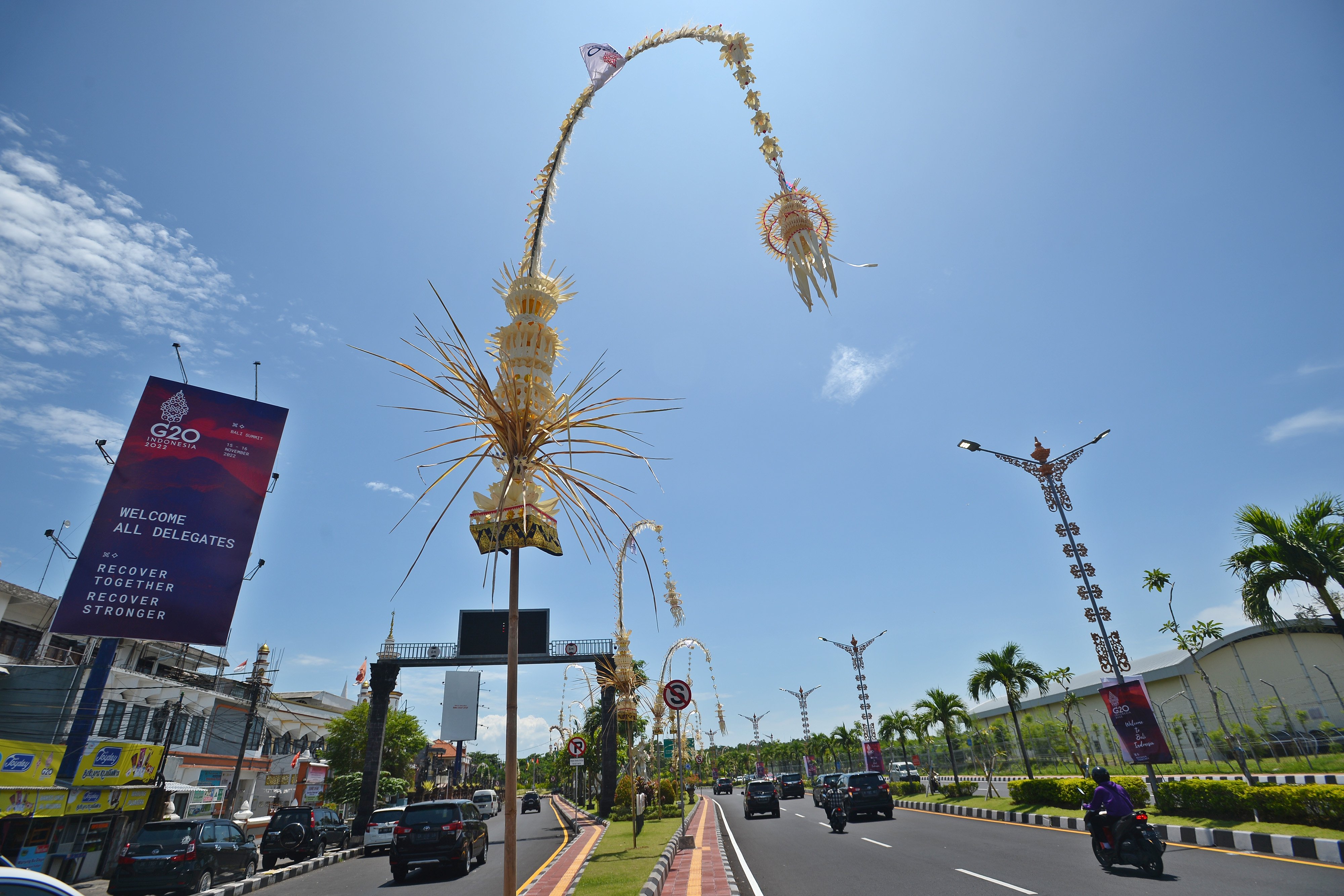 Kendaraan melintas di jalan wilayah Bali yang pinggirnya dihiasi baliho KTT G20 dan janur kuning.