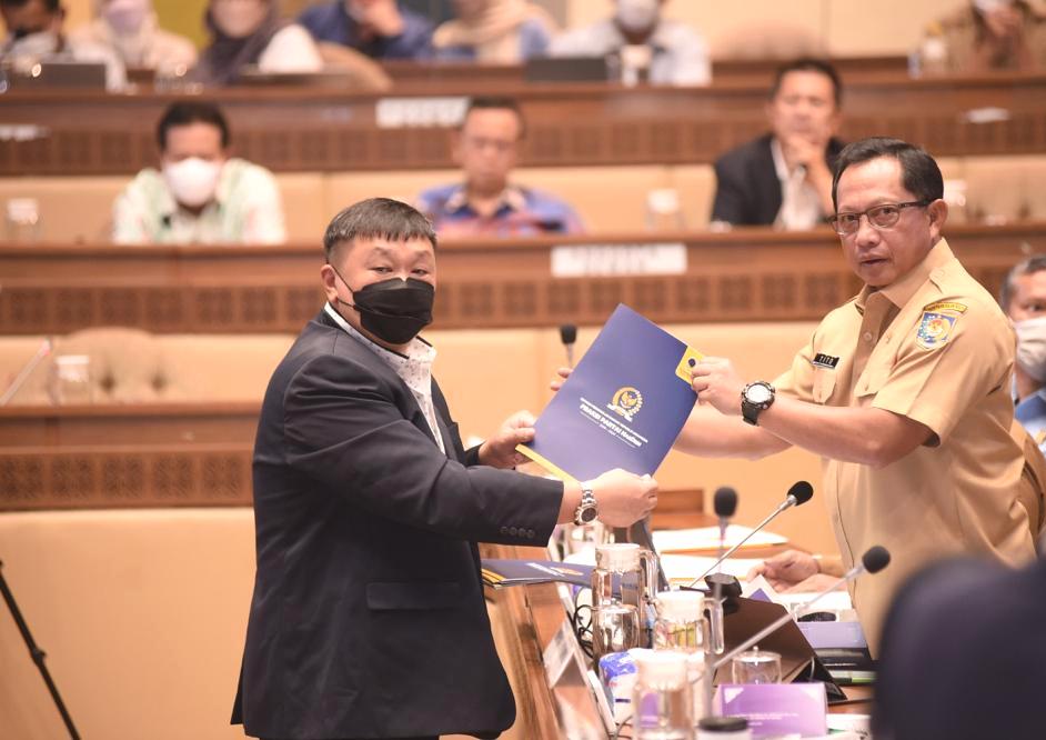 Rico Sia menyerahkan dokumen kepada Mendagri Tito Karnavian.