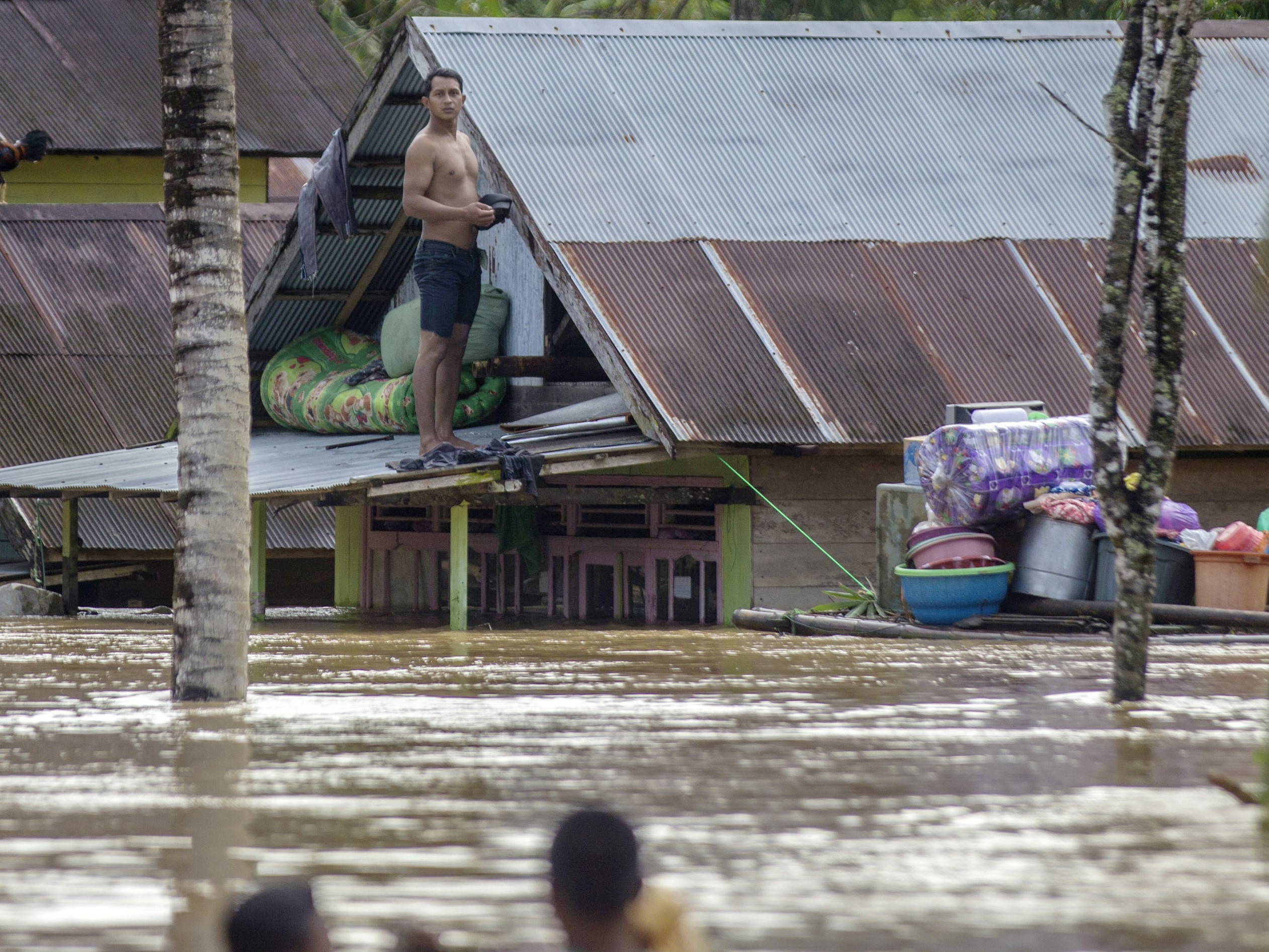 Warga berada di atap rumahnya saat terjadi banjir di Desa Pengaron, Kabupaten Banjar, Kalimantan Selatan, Rabu (12/1).