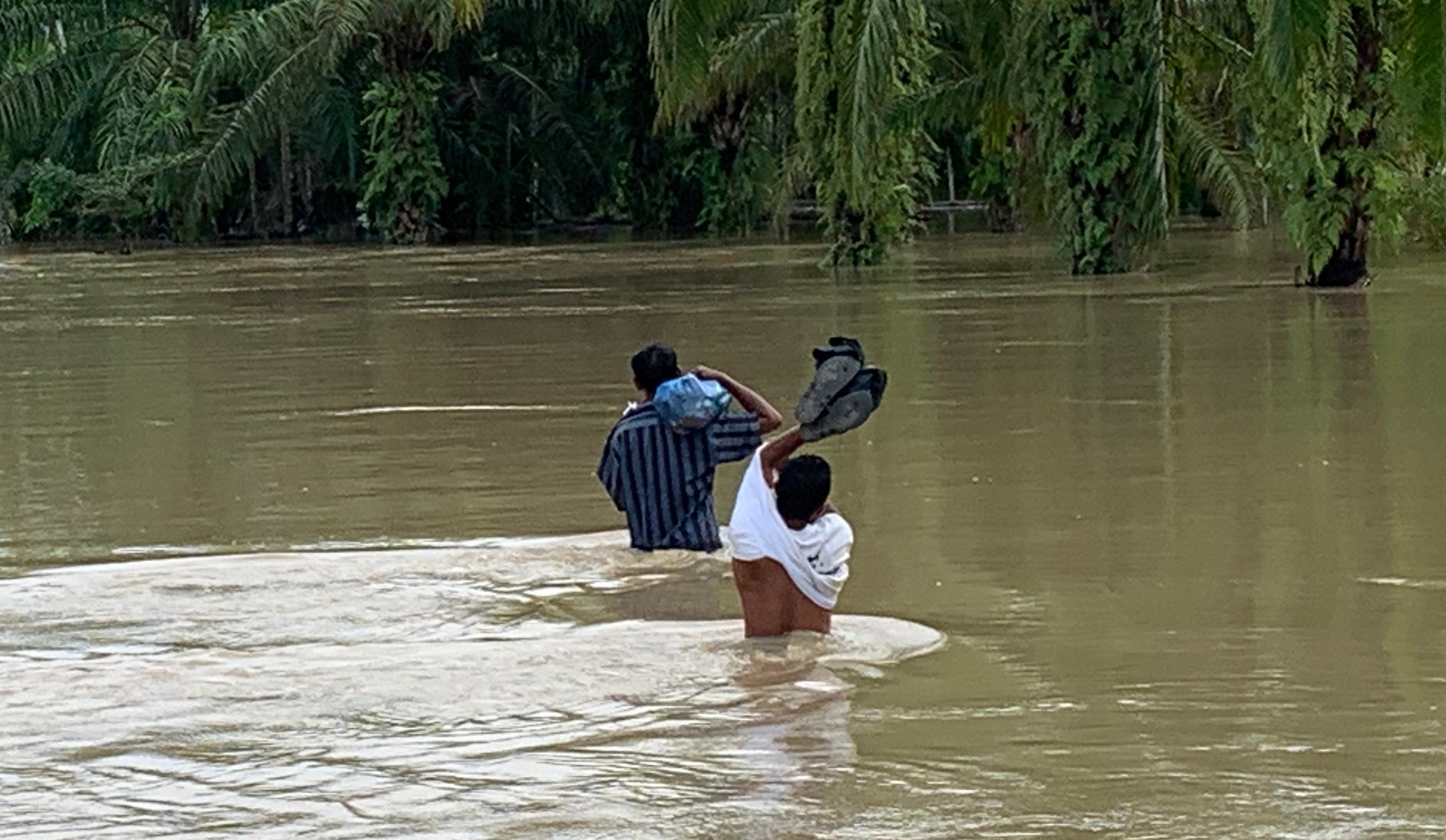 Dua orang warga sedang mengarungi banjir di Kecamatan Matangkuli, Kabupaten Aceh Utara, Provinsi Aceh, beberapa waktu lalu. 