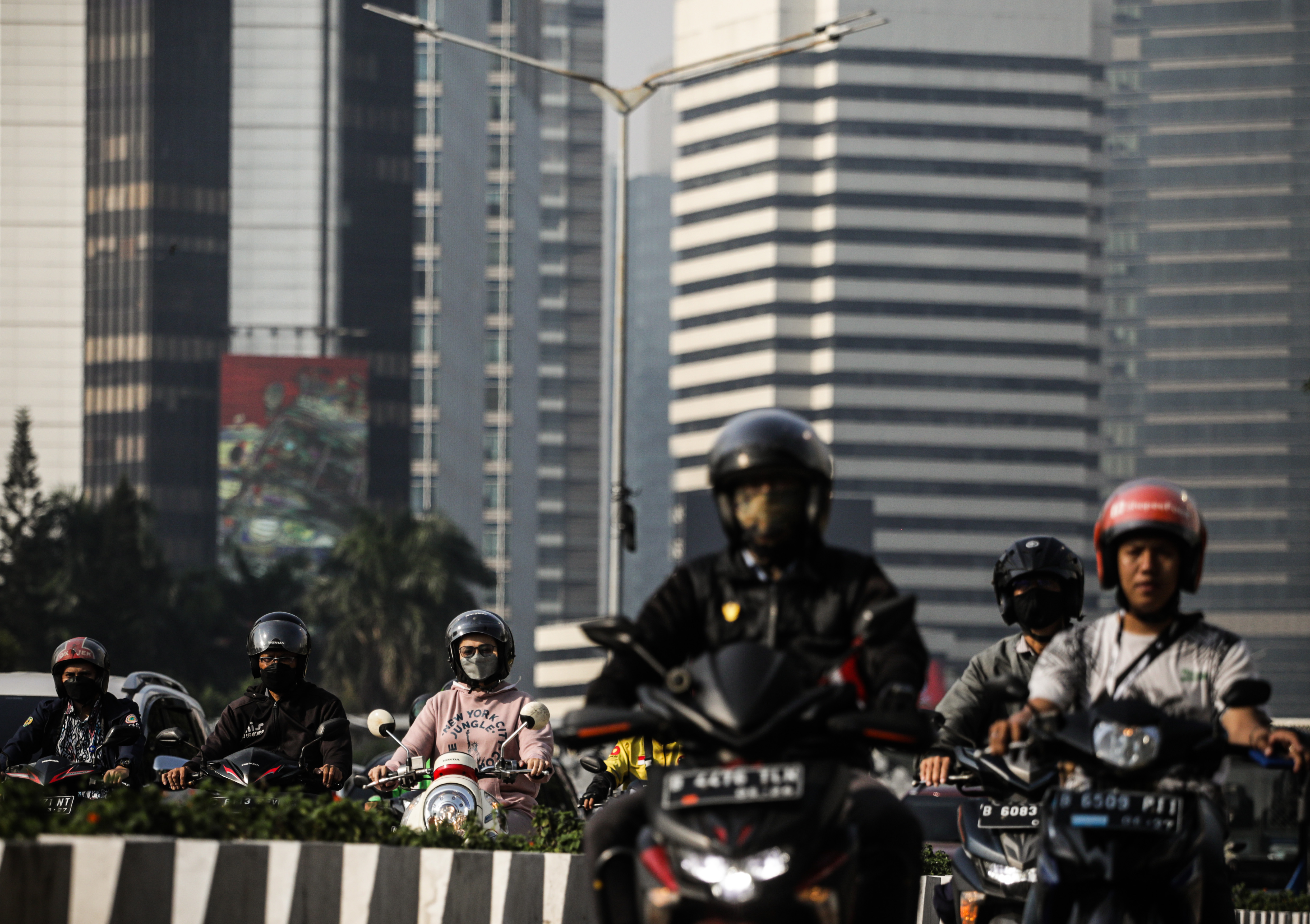 Pekerja mengendarai motor menuju kantor di kawasan Sudirman, Jakarta.