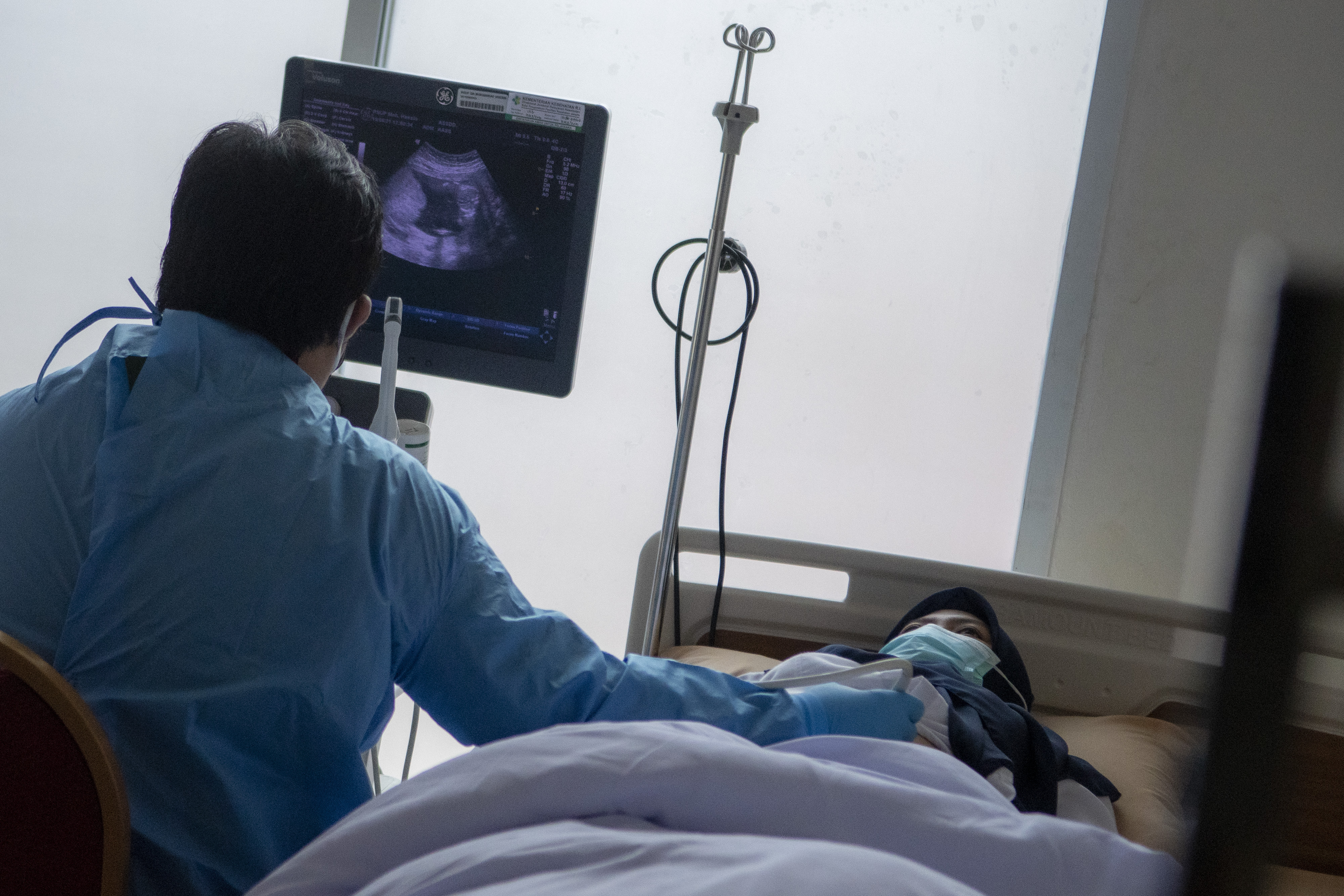 Potret dokter melakukan pemeriksaan USG kepada ibu hamil.