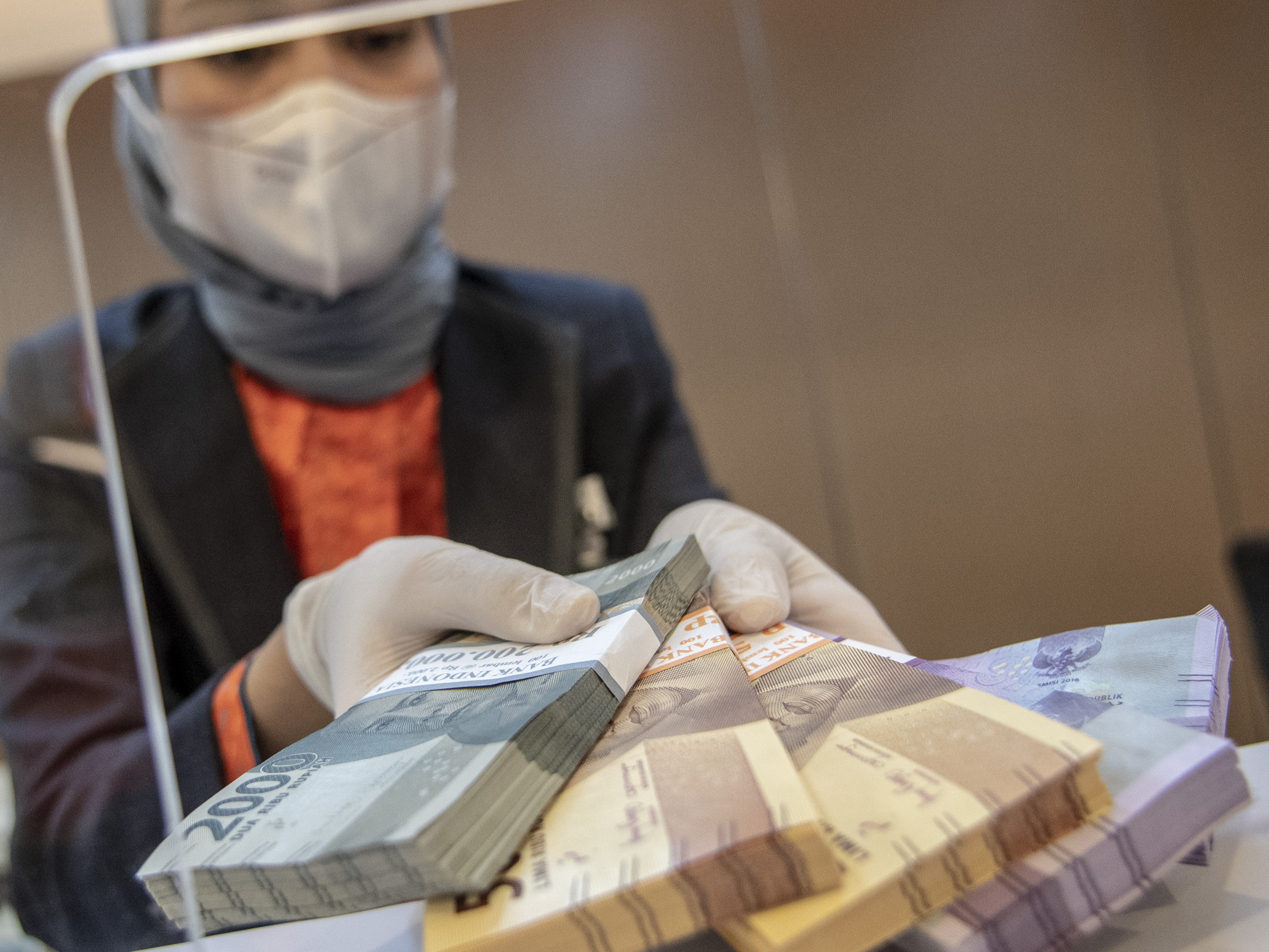 Petugas bank menunjukkan uang pecahan rupiah di BNI KC Mega Kuningan, Jakarta, Selasa (22/11/2022).