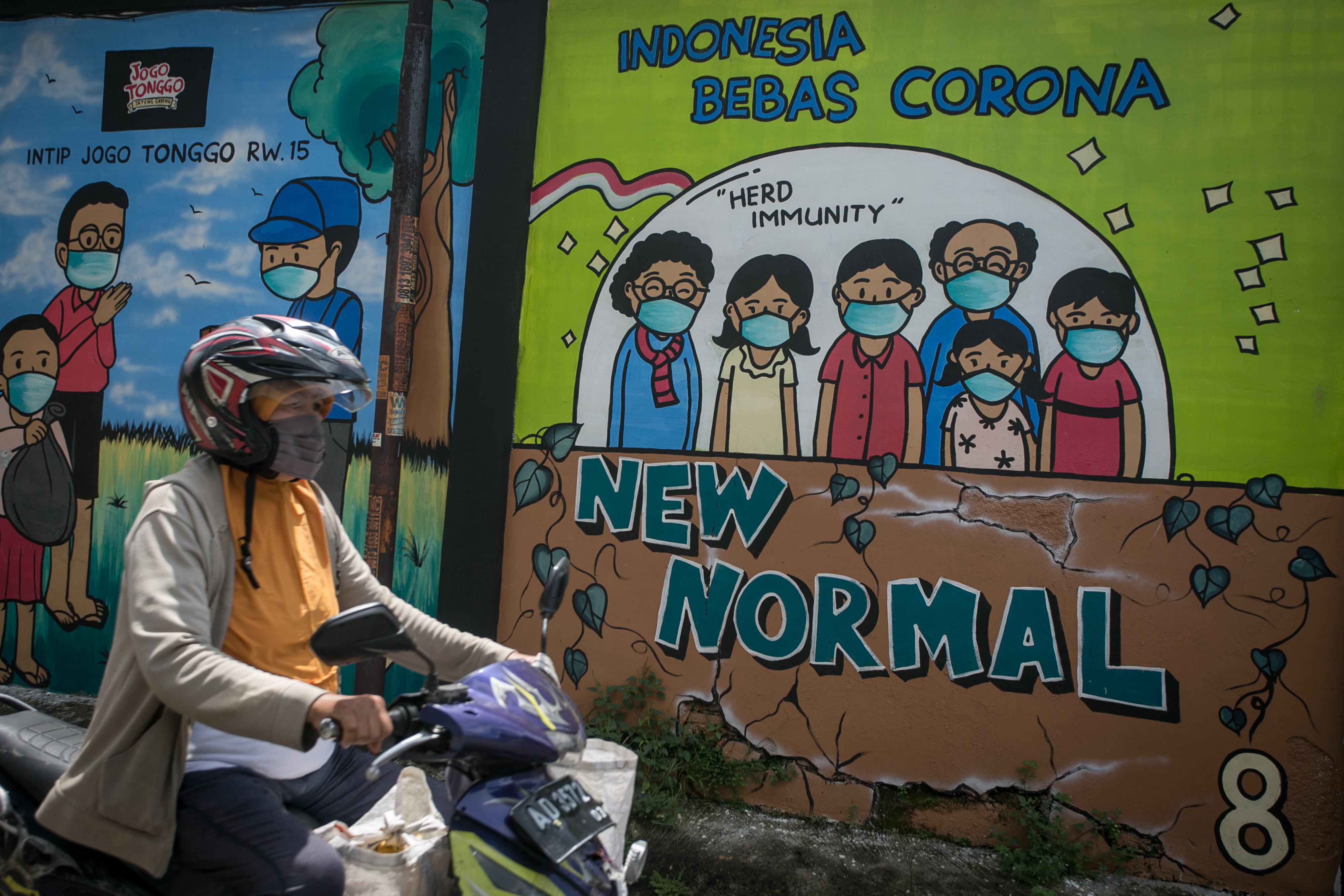 Warga melintasi mural terkait pandemi covid-19.