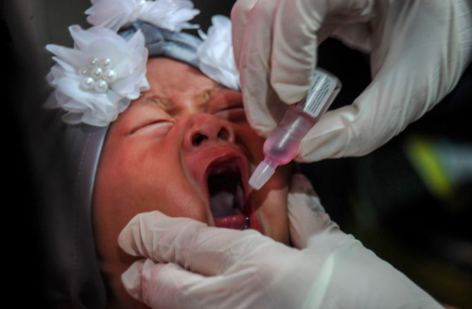 Tenaga medis memberikan imunisasi polio kepada seorang balita.