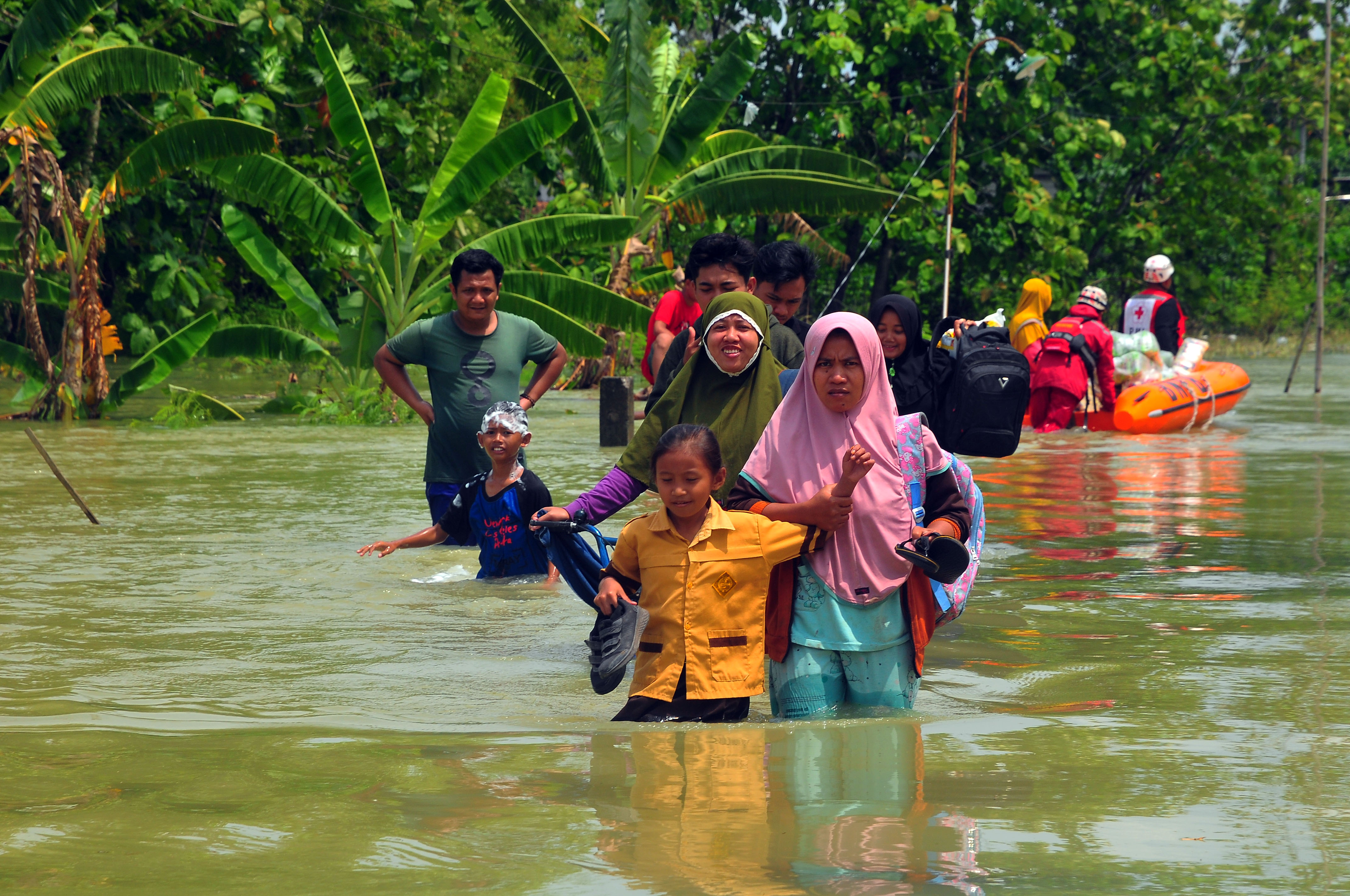 Warga berjalan melewati jalan yang tergenang air di Desa Kedungrejo, Kecamatan Grobogan, Grobogan, Jawa Tengah.