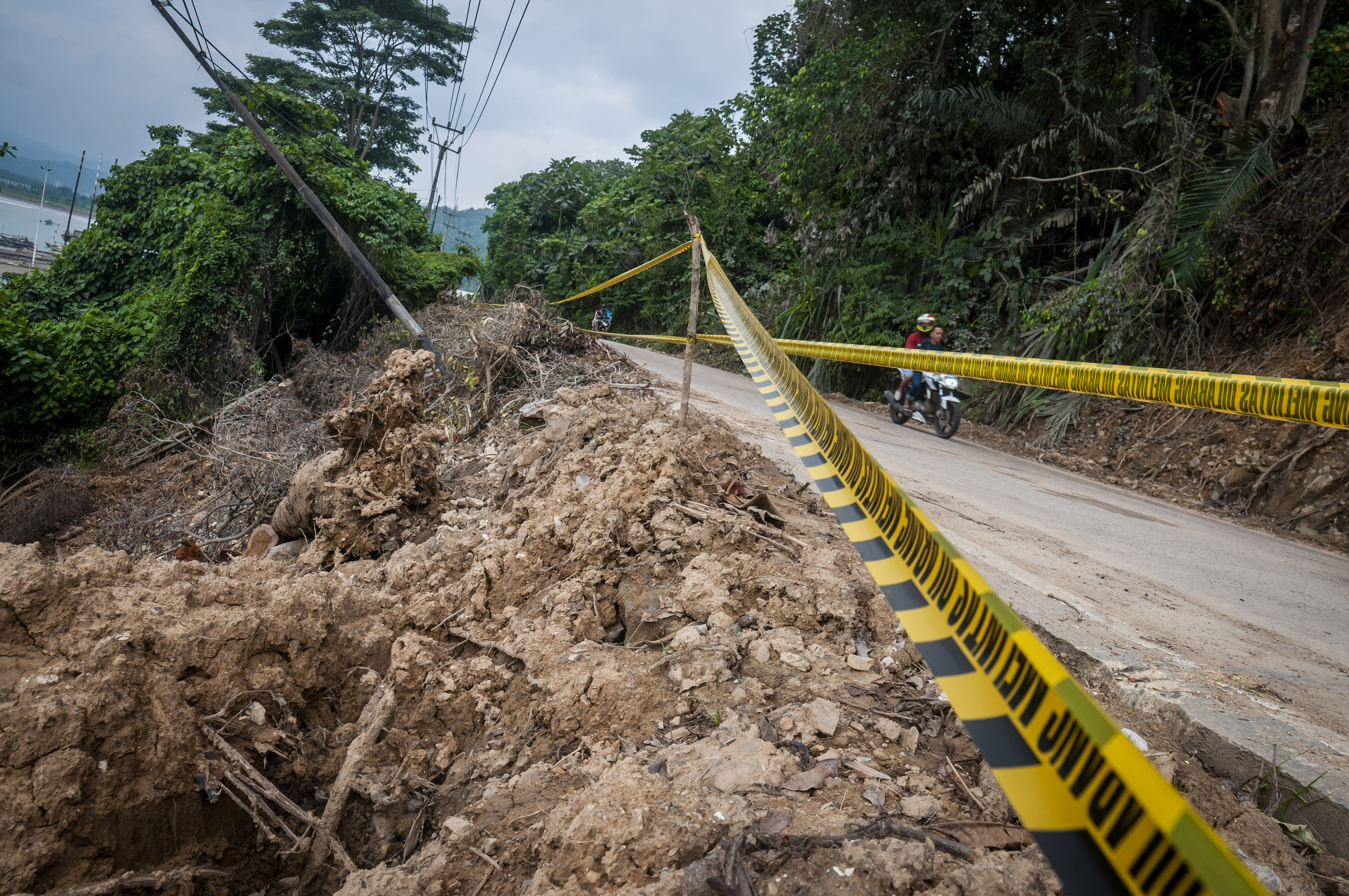 HIMBAUAN WASPADA LONGSOR: Pengendara sepeda motor melintas di salah satu ruas jalan bekas terkena longsor di Bayah, Lebak, Banten.