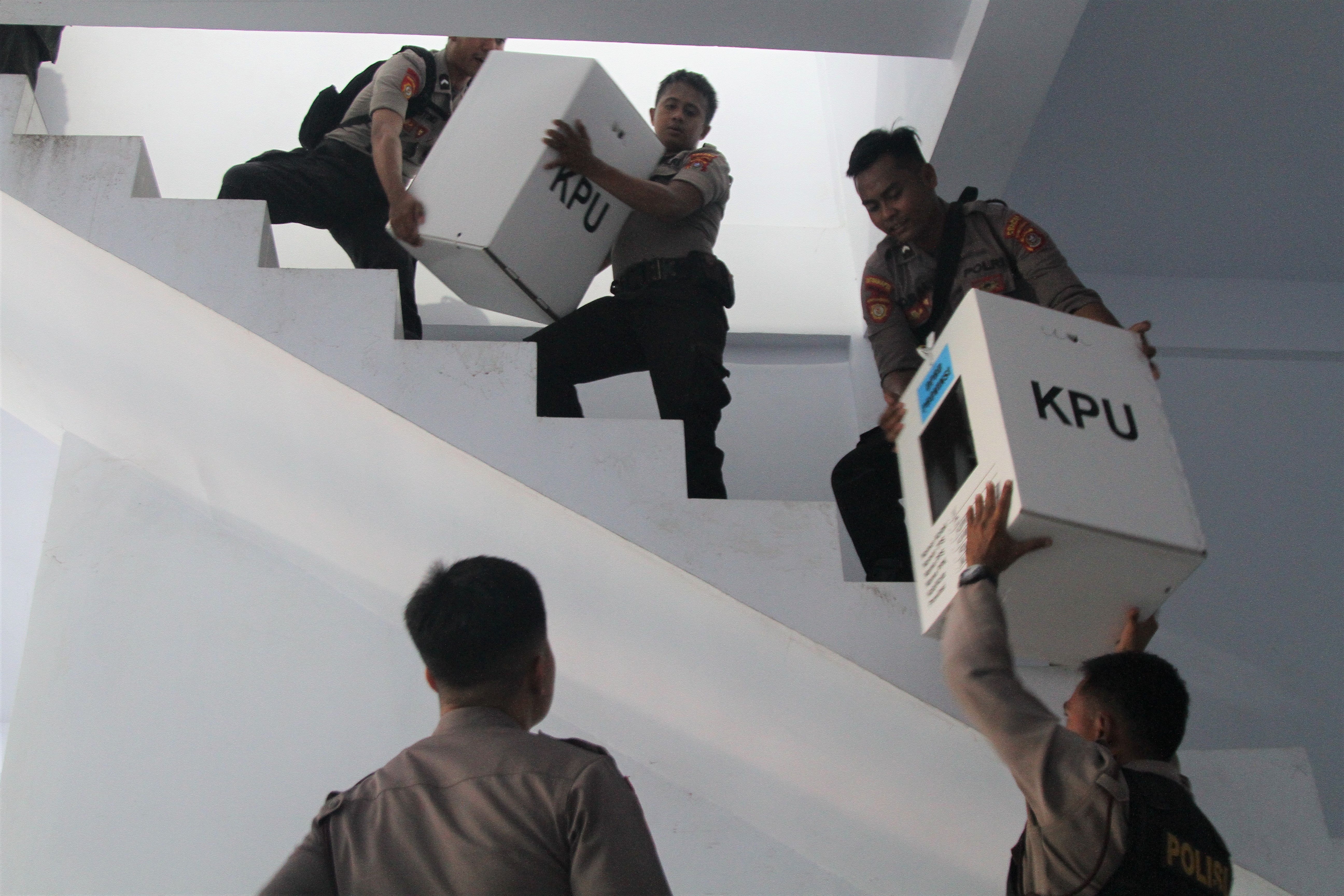 Petugas kepolisian membantu distribusi logistik pemilu.