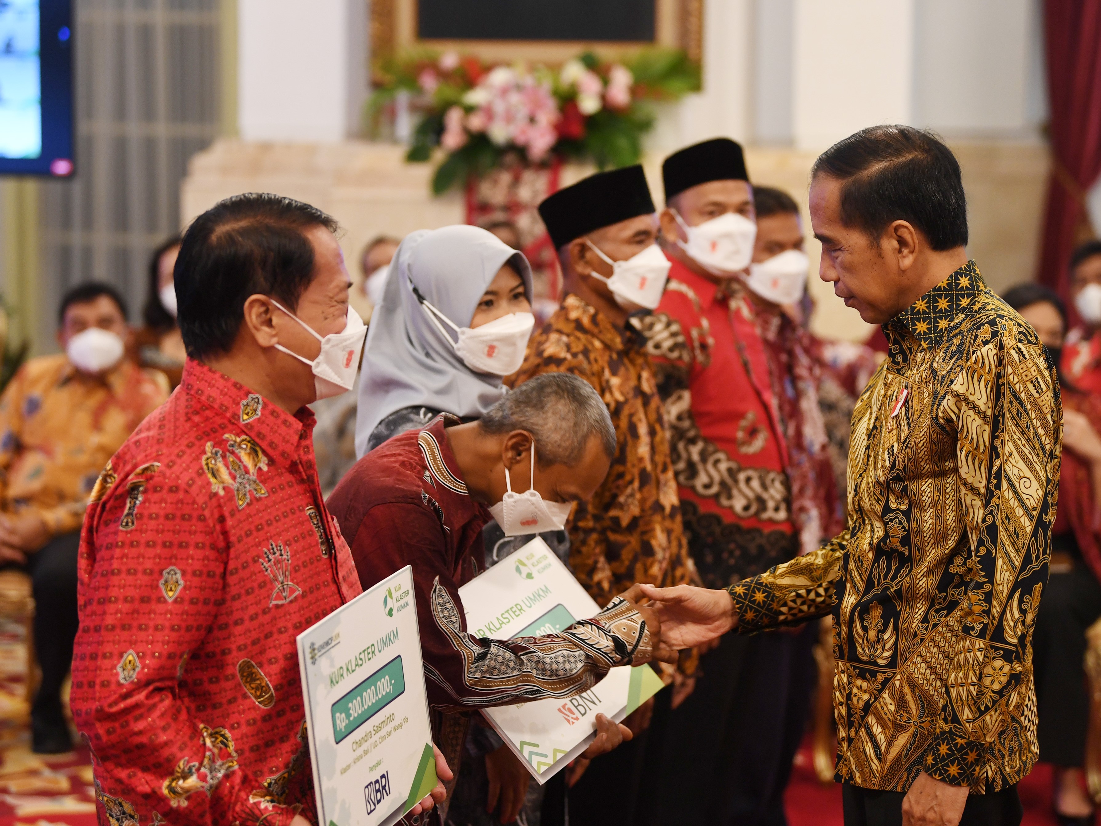 Presiden Joko Widodo (kanan) menyerahkan kredit usaha rakyat (KUR) klaster kepada pelaku UMKM di Istana Negara, Jakarta, Senin (19/12).