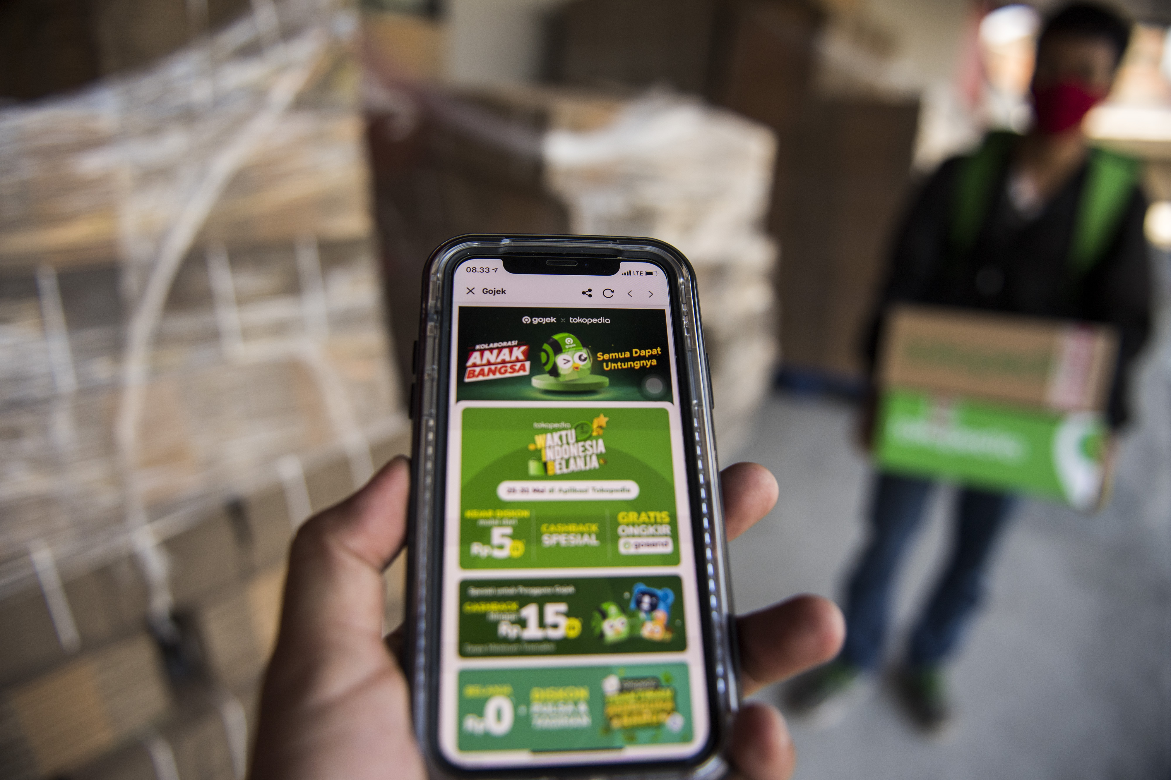 Pengemudi Gojek membawa kemasan paket dari Tokopedia.