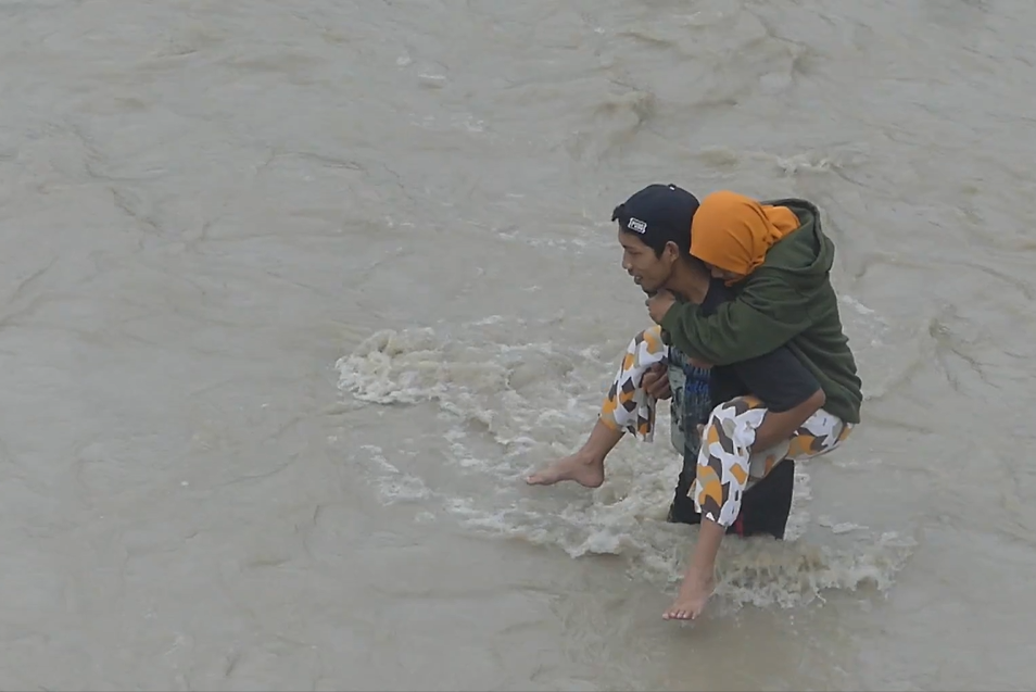 Warga menyeberangi sungai.