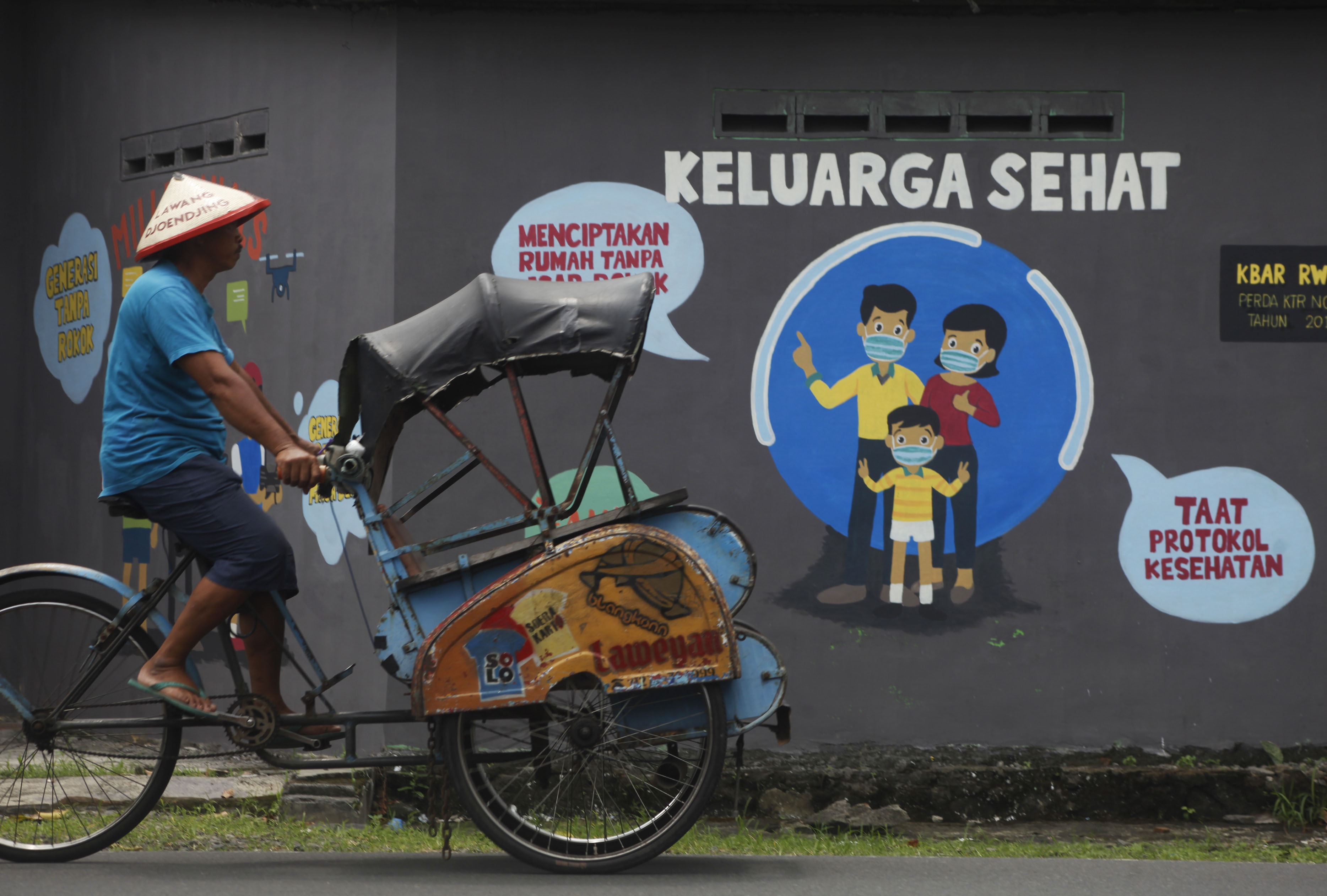 Warga melintas di depan mural terkait pandemi covid-19.