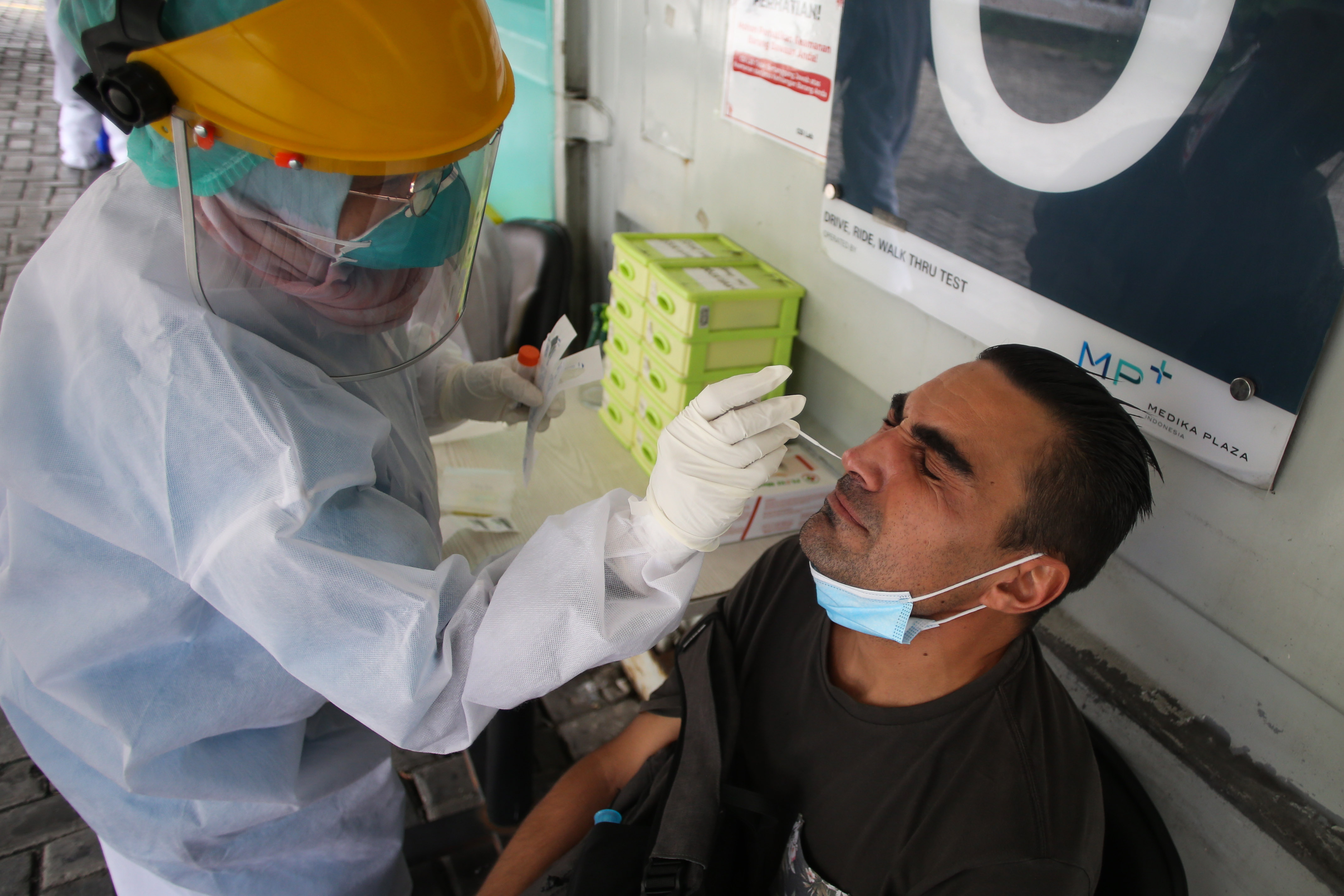 Petugas medis melakukan tes swab PCR kepada warga di laboratorium wilayah Jakarta.
