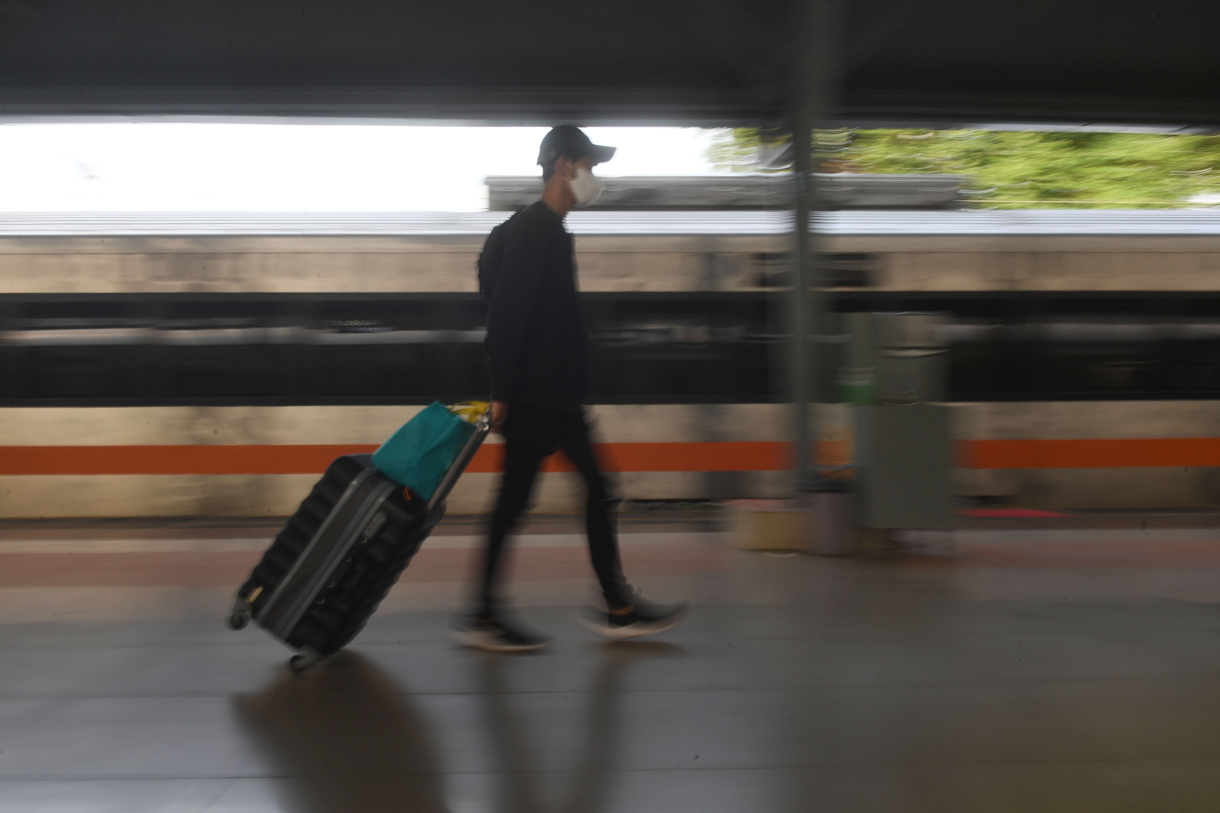 Potret penumpang berjalan di stasiun setelah turun dari kereta api jarak jauh.