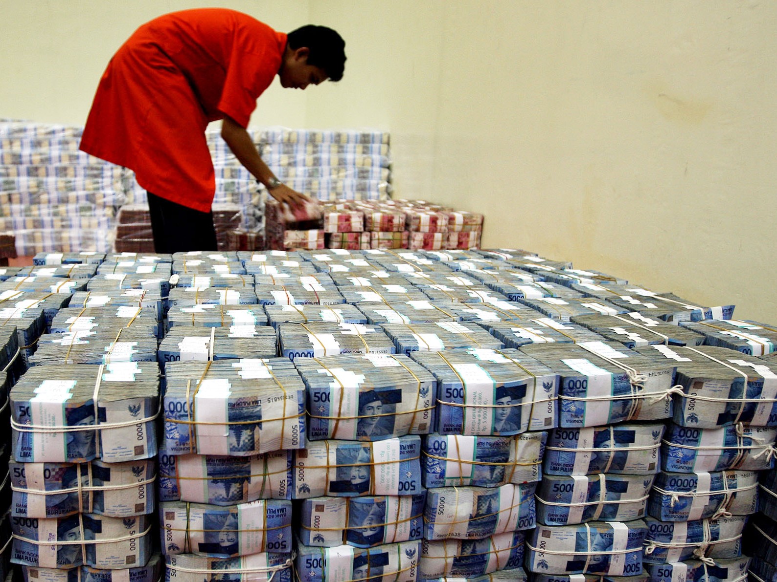 Seorang petugas tengah menata tumpukan uang miliaran rupiah di ruang cash centre Bank BNI Jakarta.