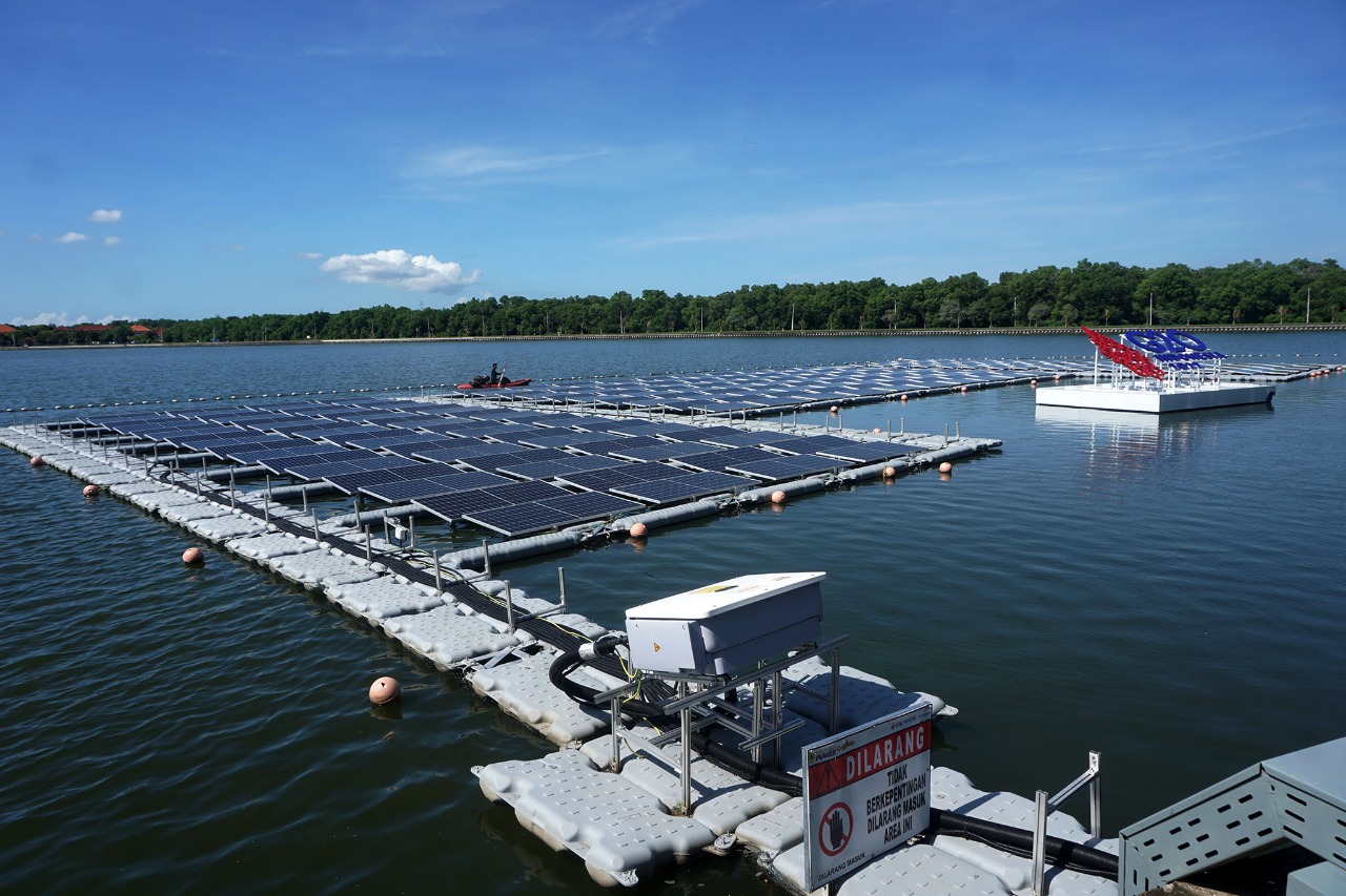 Pekerja tengah membersihkan sampah di PLTS Terapung Waduk Muara Nusa Dua yang dimiliki oleh PLN Grup.