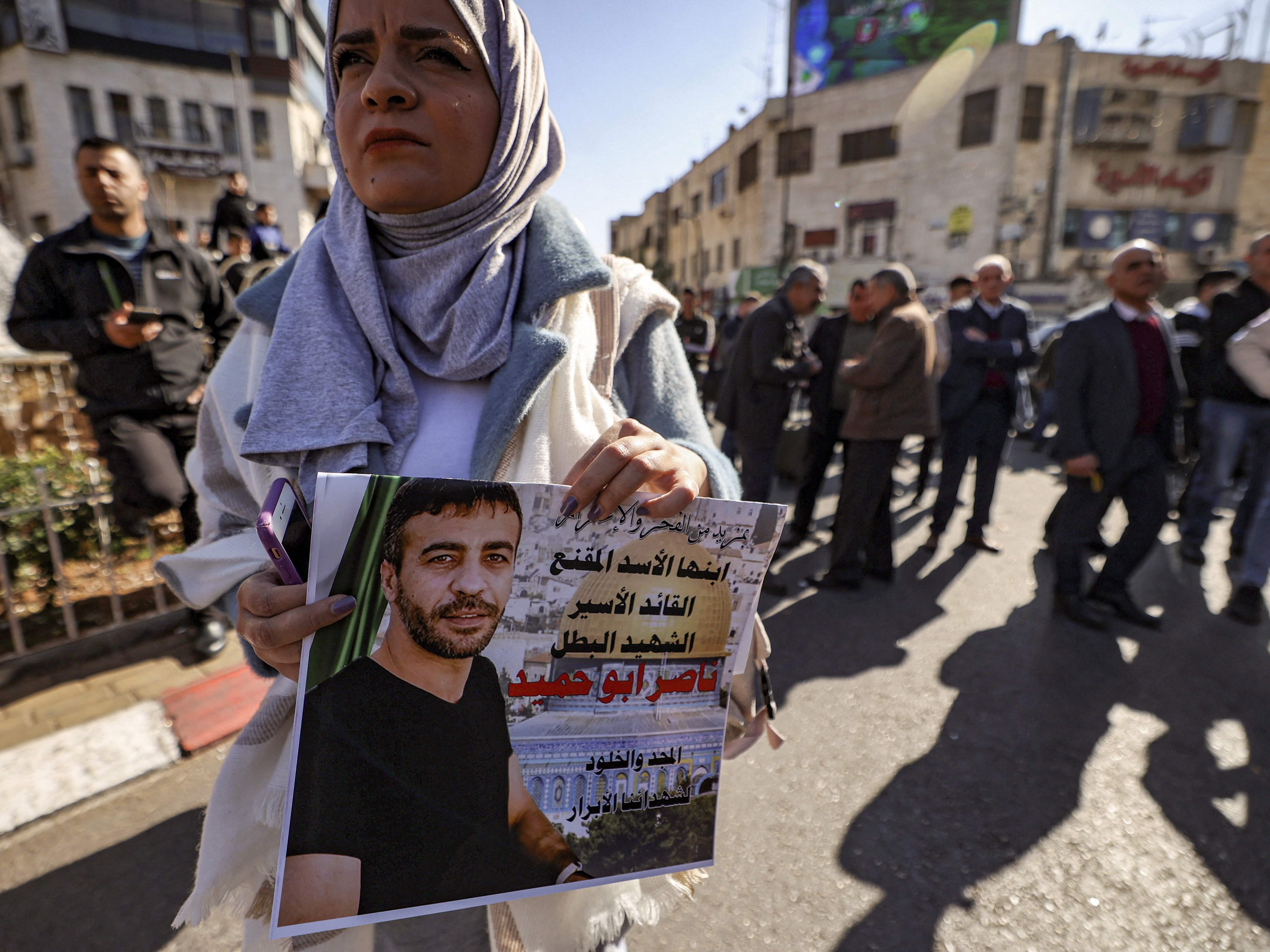 Seorang wanita memegang gambar wajah tahanan Palestina Nasser Abu Hamid yang meninggal di penjara Israel.