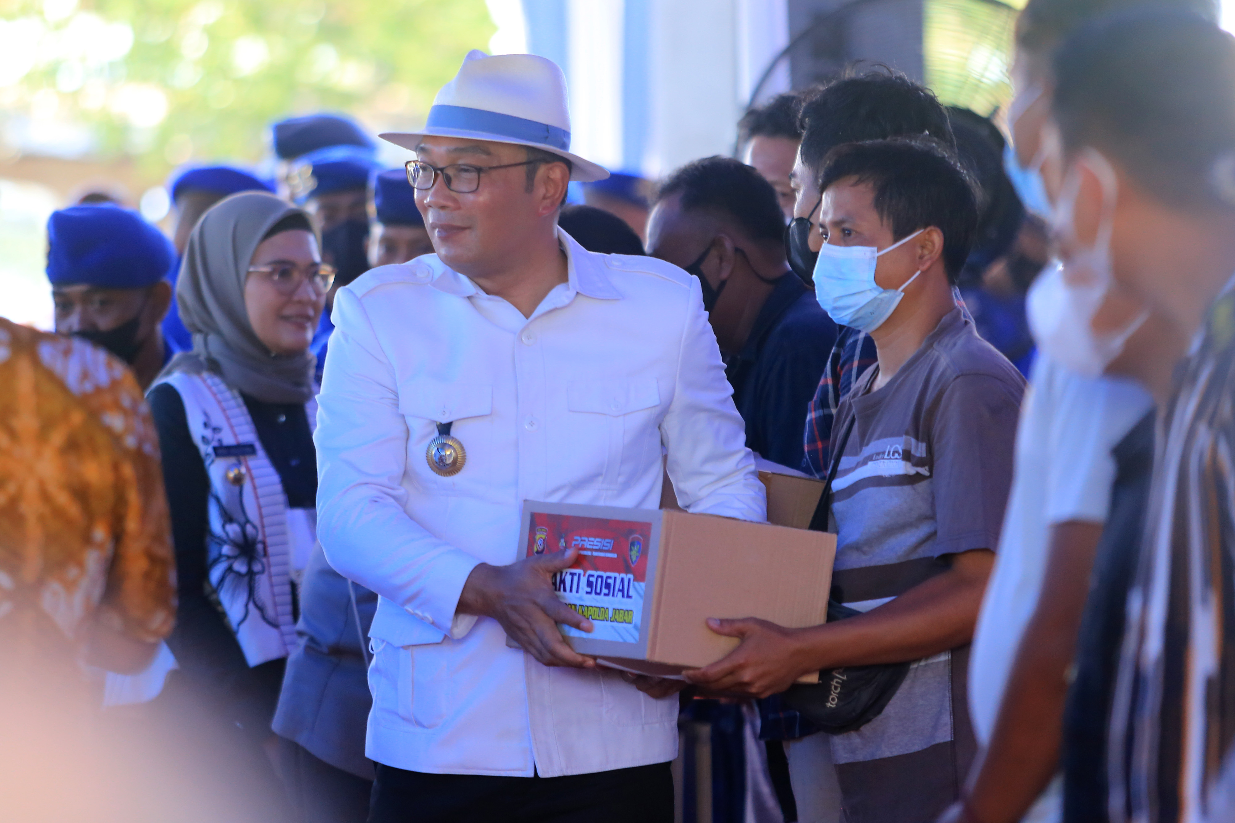 Gubernur Jawa Barat Ridwan Kamil (kiri) menyerahkan paket sembako kepada warga saat bakti sosial di kampung nelayan Karangsong, Indramayu, J