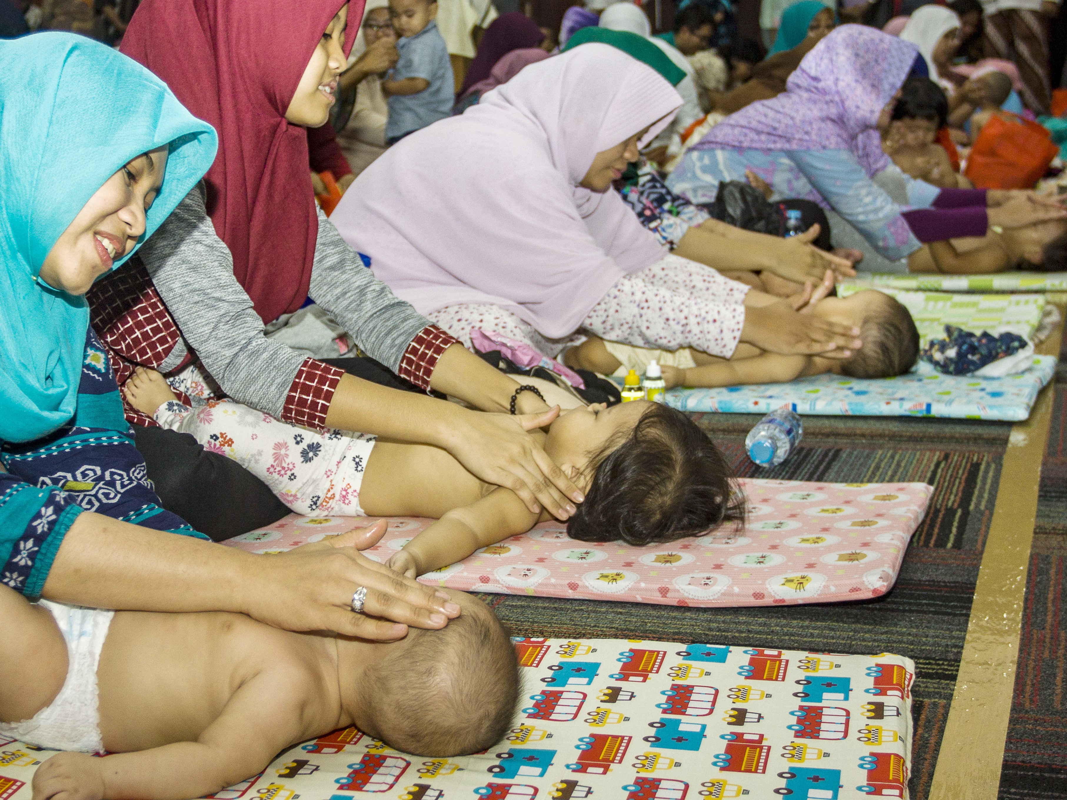 Peserta pijat bayi memijat anaknya saat kegiatan pijat bayi massal di Kementerian Kesehatan, Jakarta.