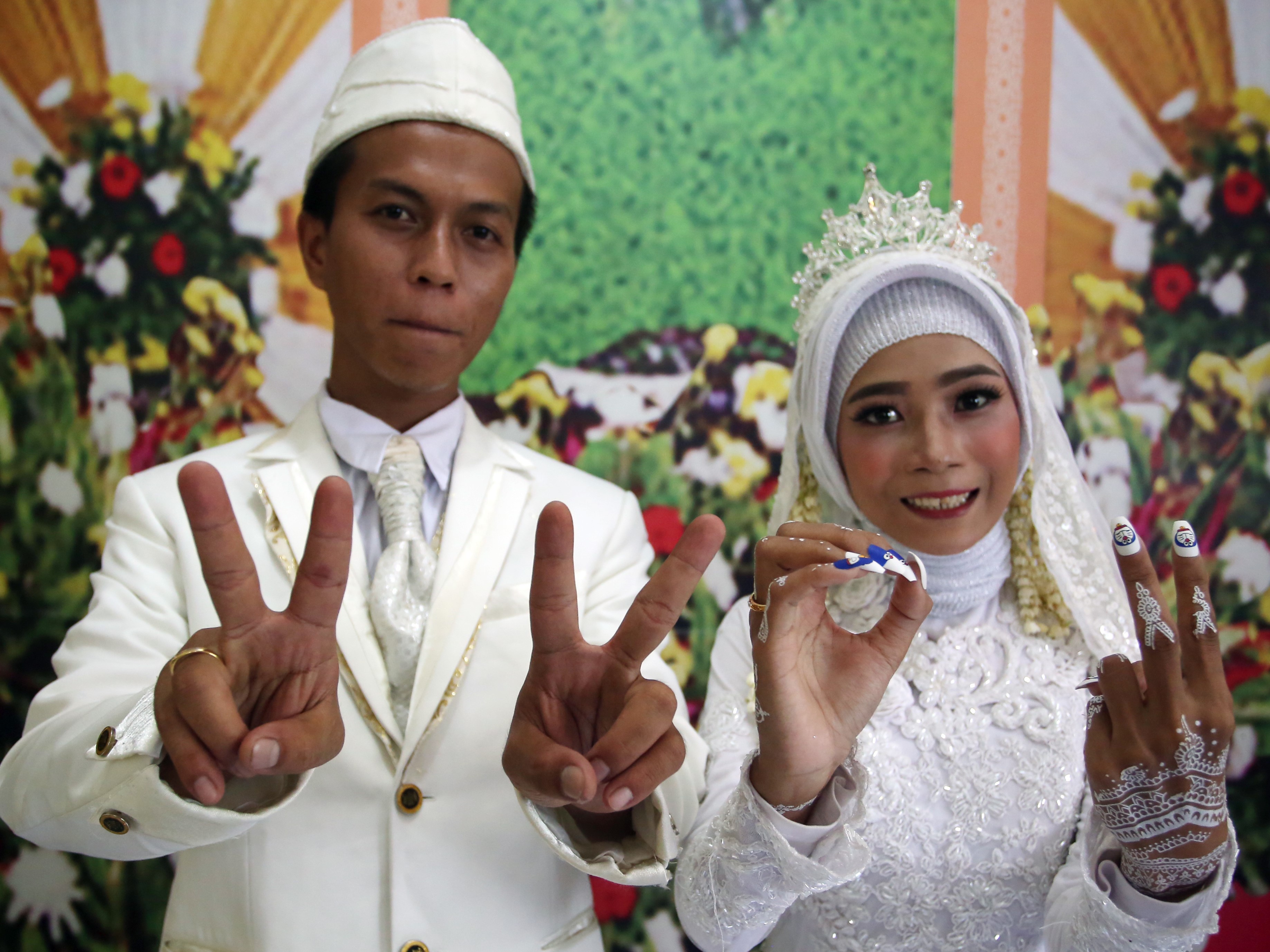 Sepasang pengantin menunjukan simbol 22022022 usai melangsungkan pernikahan di KUA Pamulang, Pamulang, Tangsel, Banten, Selasa (22/2).