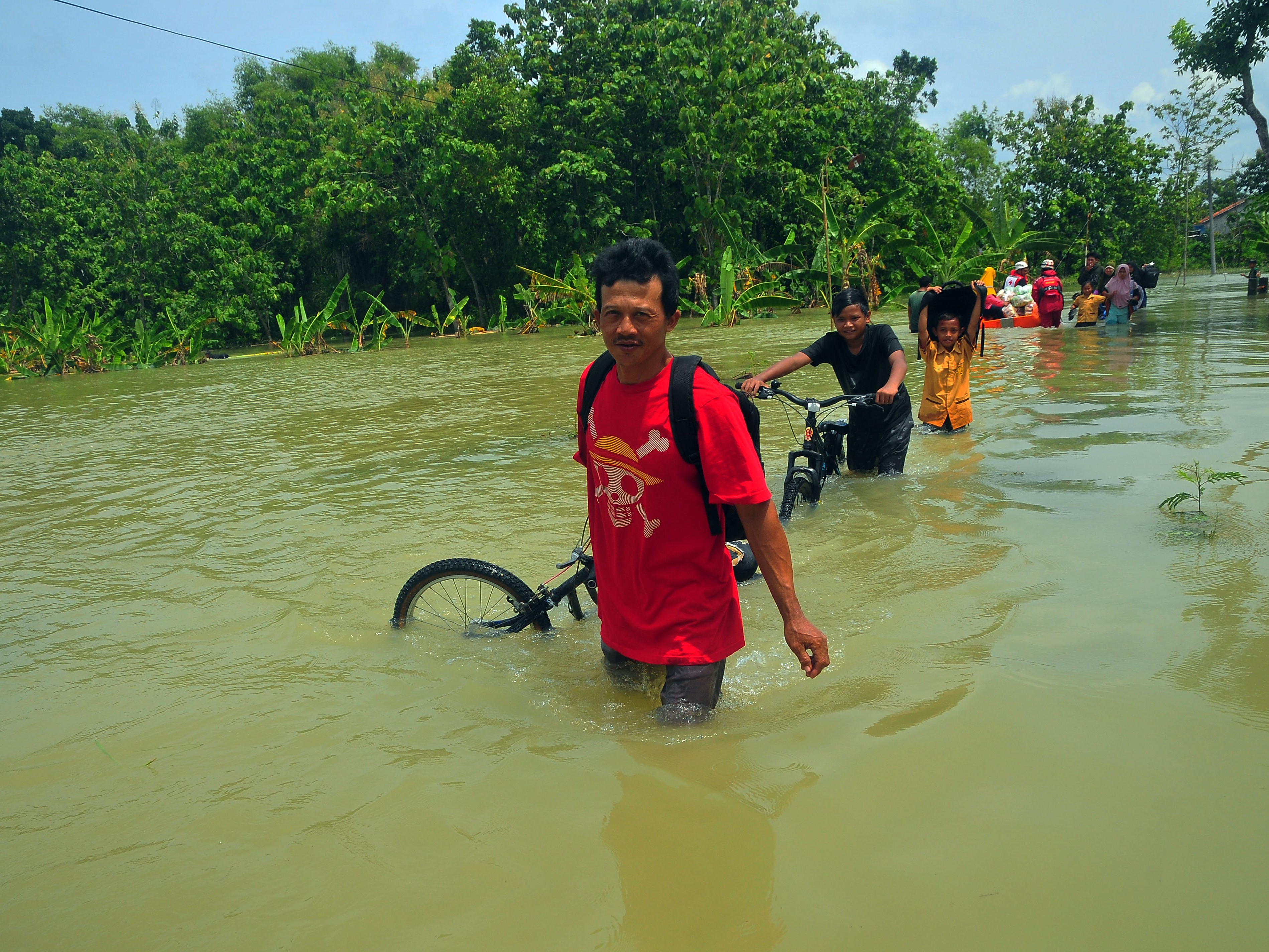 Warga berjalan melewati jalan yang tergenang air di Desa Kedungrejo, Kecamatan Grobogan, Grobogan, Jawa Tengah, Sabtu (3/12/2022).