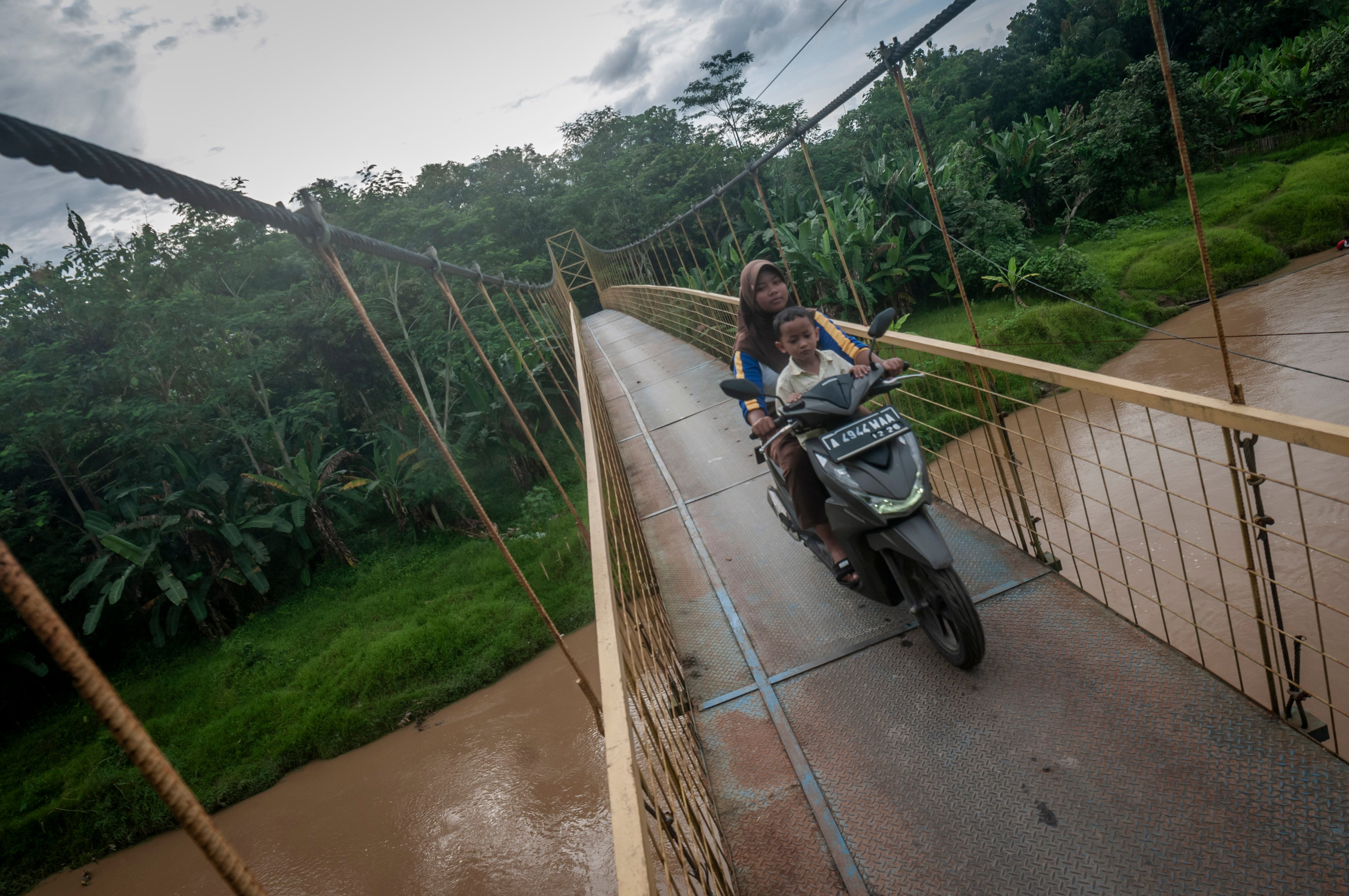 Warga mengendarai sepeda motor melintasi jembatan gantung yang dibangun dari dana desa di Cimarga, Lebak, Banten, Kamis (8/12).