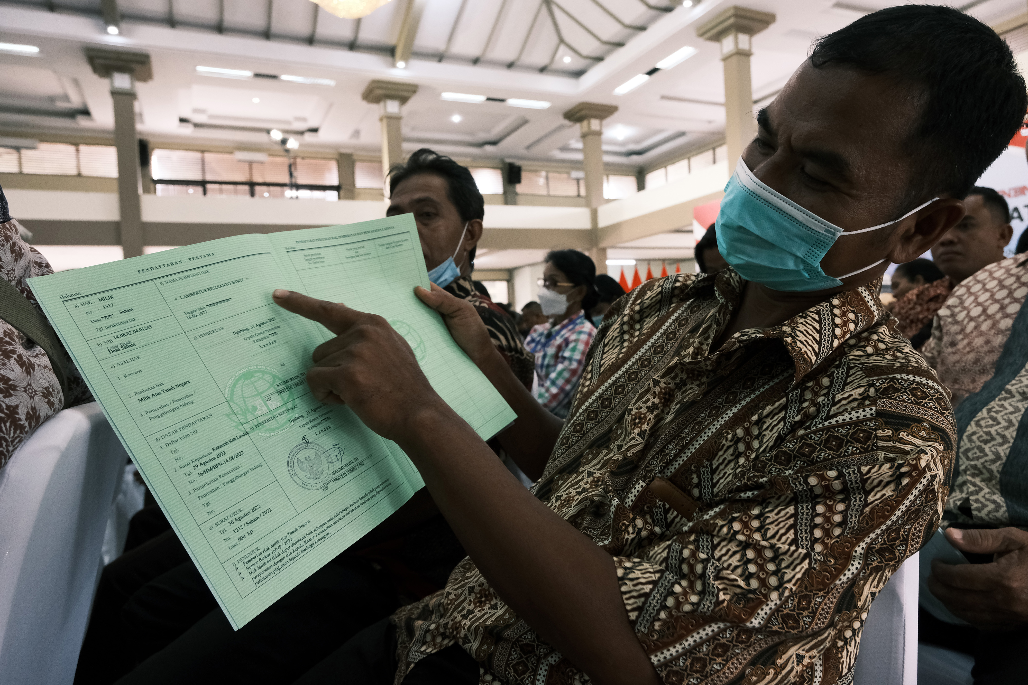 Warga memperlihatkan sertifikat tanah yang baru saja diterima dari pemerintah.