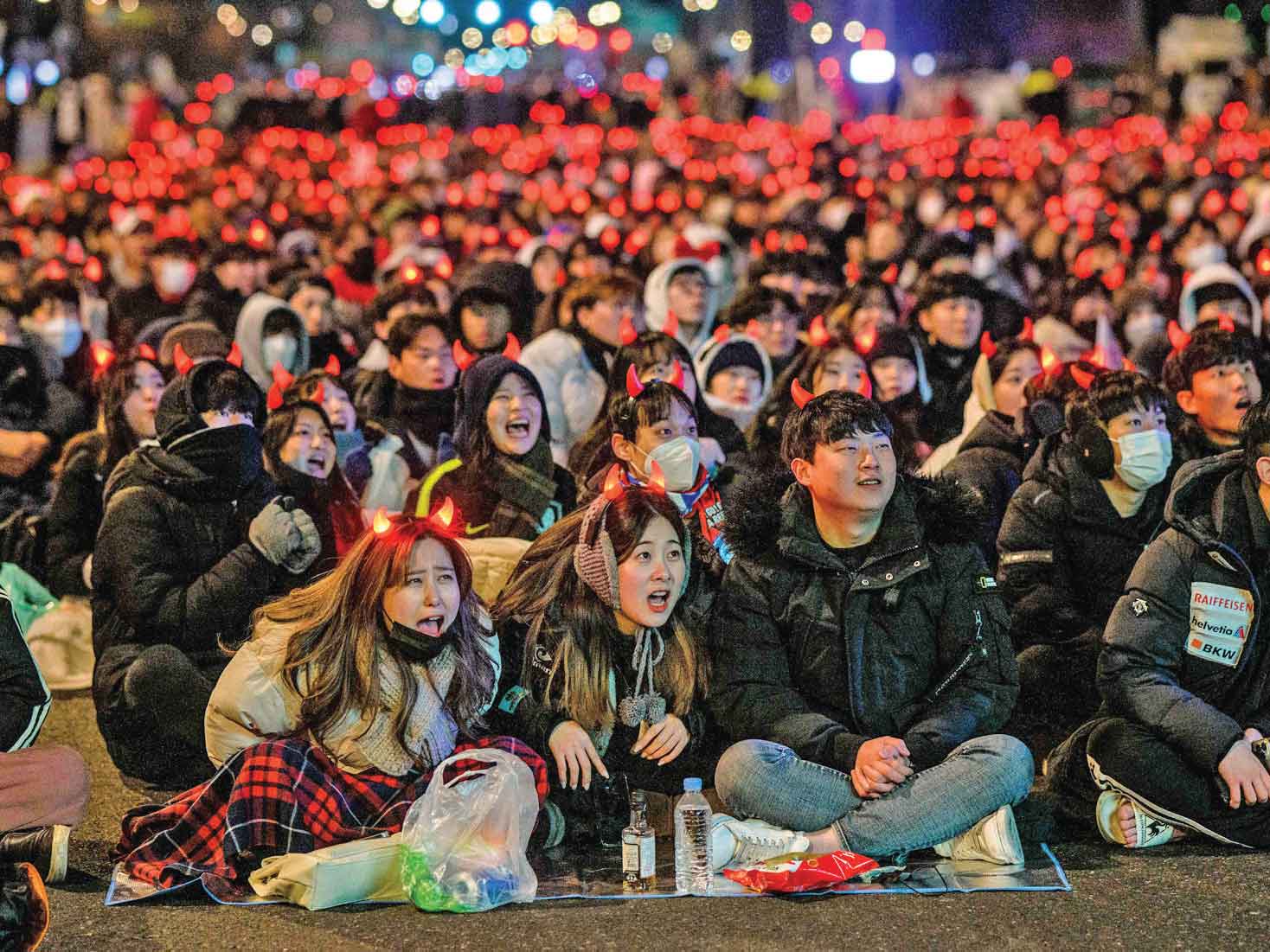 TANPA MASKER: Sebagian besar warga Korsel tanpa memakai masker berkumpul menyaksikan tim nasional negaranya di tengah suasana bersalju