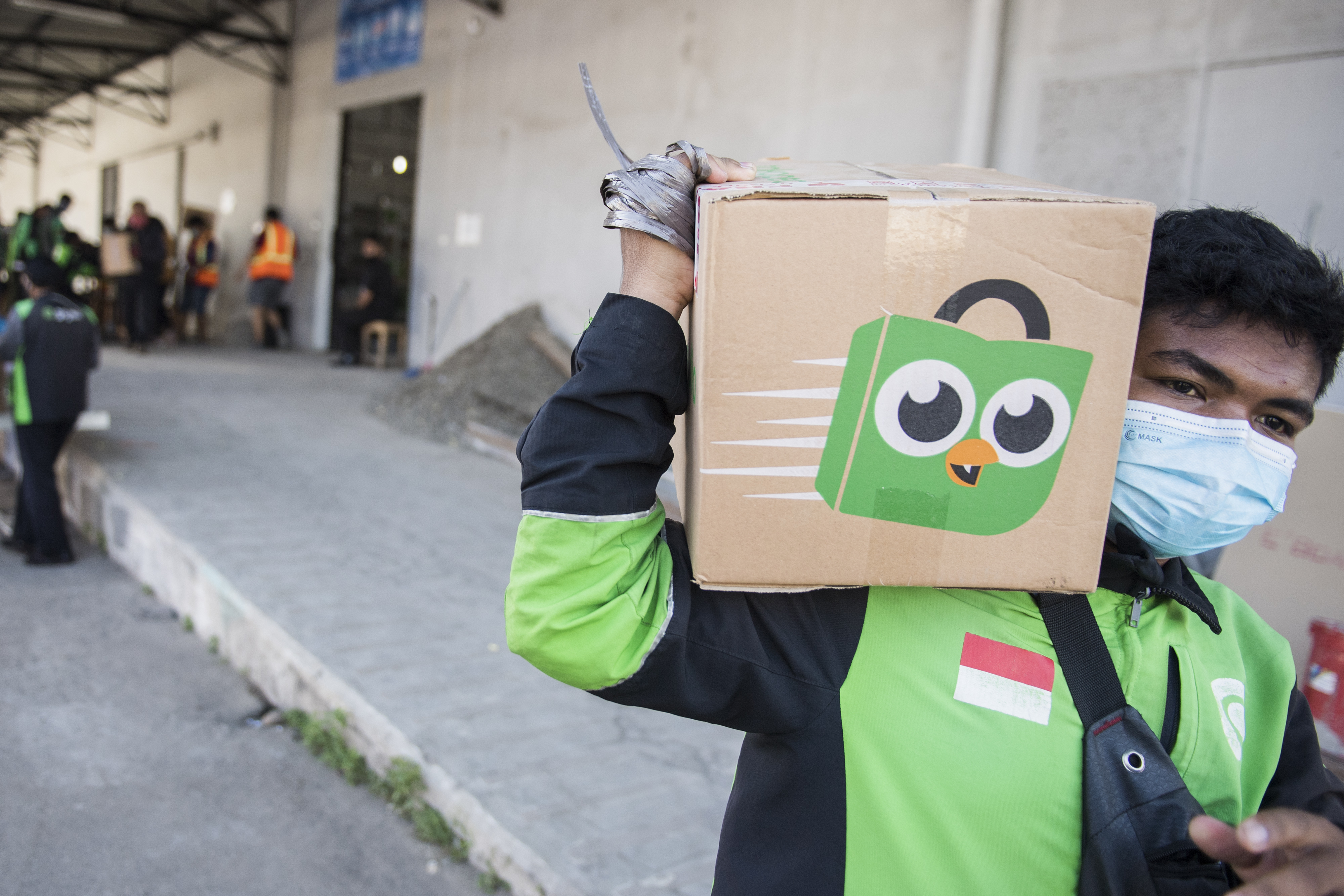 Pengemudi daring Gojek membawa kemasan paket dari Tokopedia.