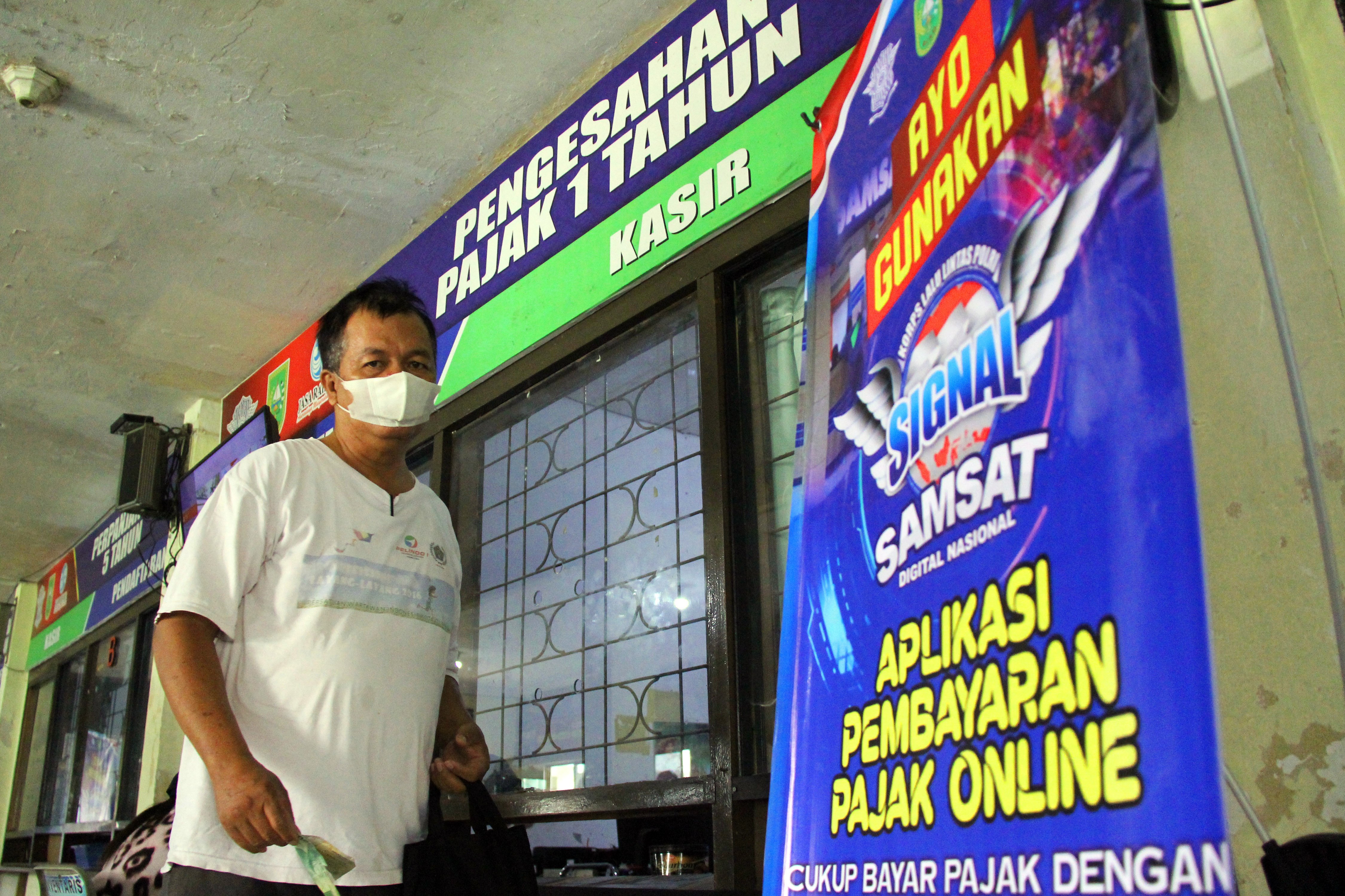 Seorang pemilik mobil mengambil STNK seusai membayar pajak di Kantor Samsat Dumai, Riau.