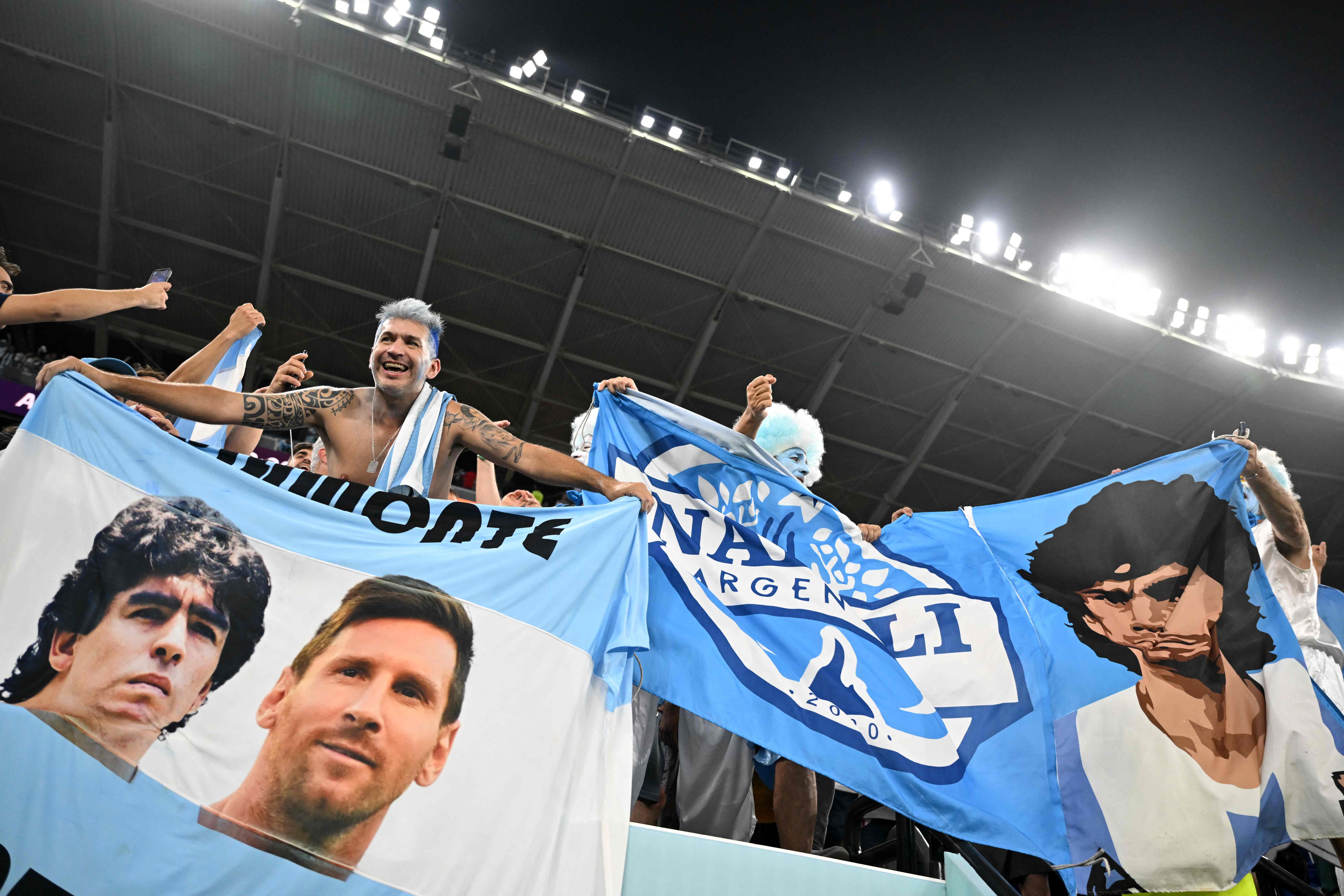 Suporter Argentina mengibarkan spanduk bergambar Lionel Messi dan Diego Maradona.
