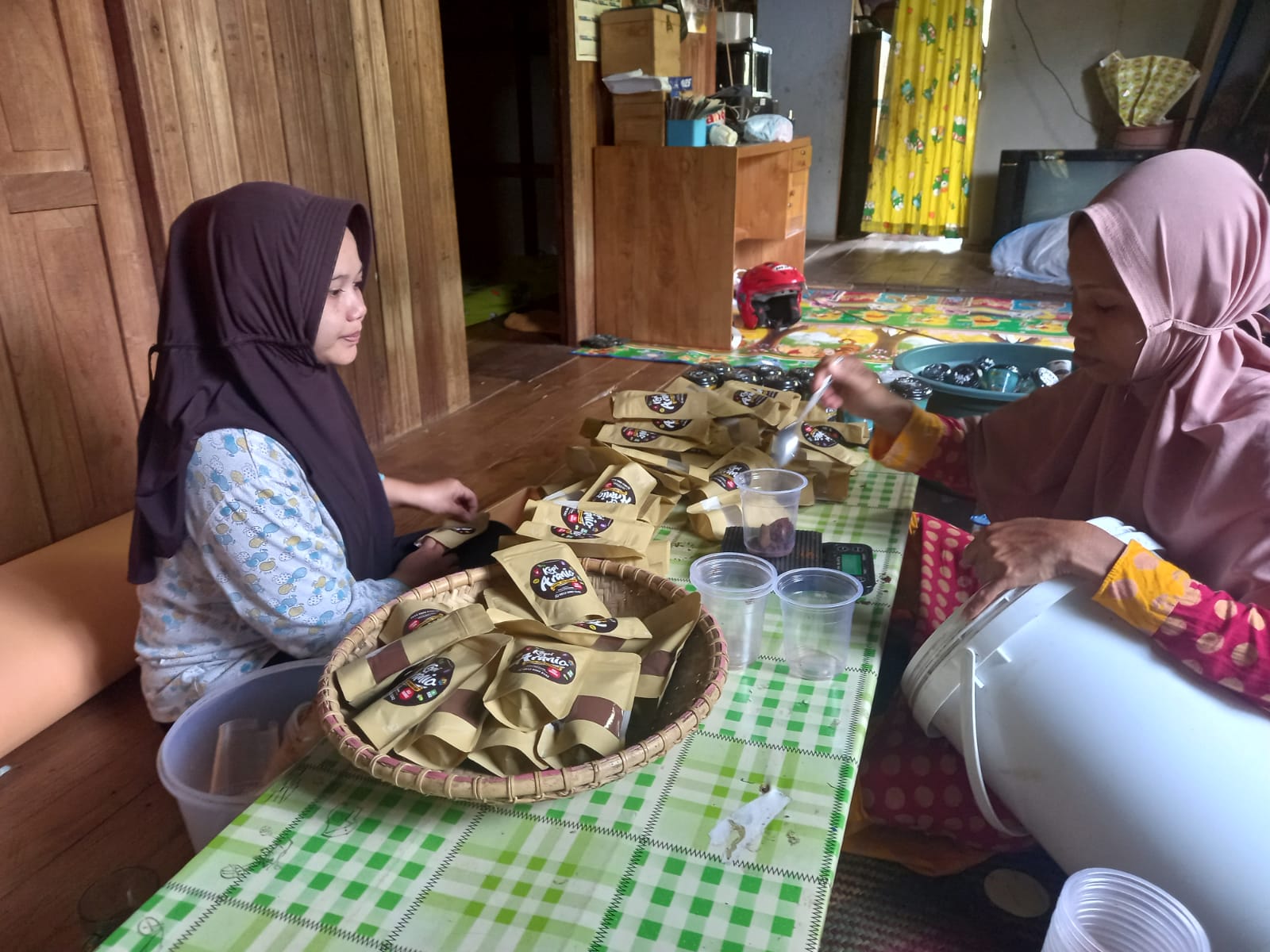 Sejumlah ibu, anggota Kelompok Tani Hutan (KTH) Tunas Muda di Desa Tiwingan Baru, Kecamatan Aranio, Kabupaten Banjar, tengah mengemas kopi.