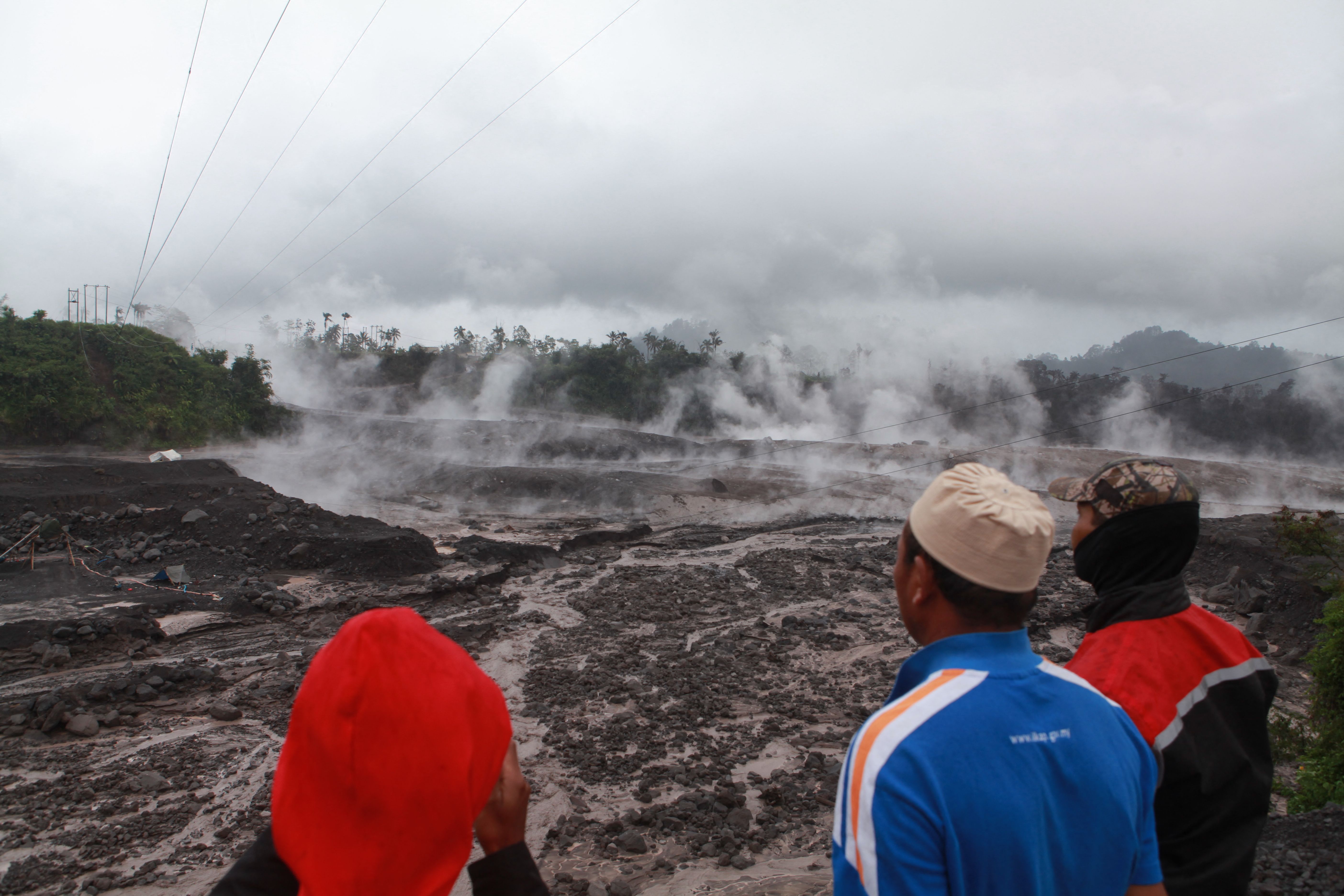 Warga menyaksikan material yang terkena awan panas guguran akibat erupsi Gunung Semeru di Lumajang, Jawa Timur, Minggu (4/12).