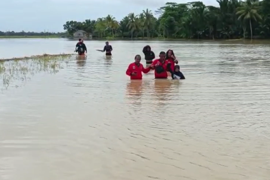Warga berjalan melintasi banjir di Pandeglang.