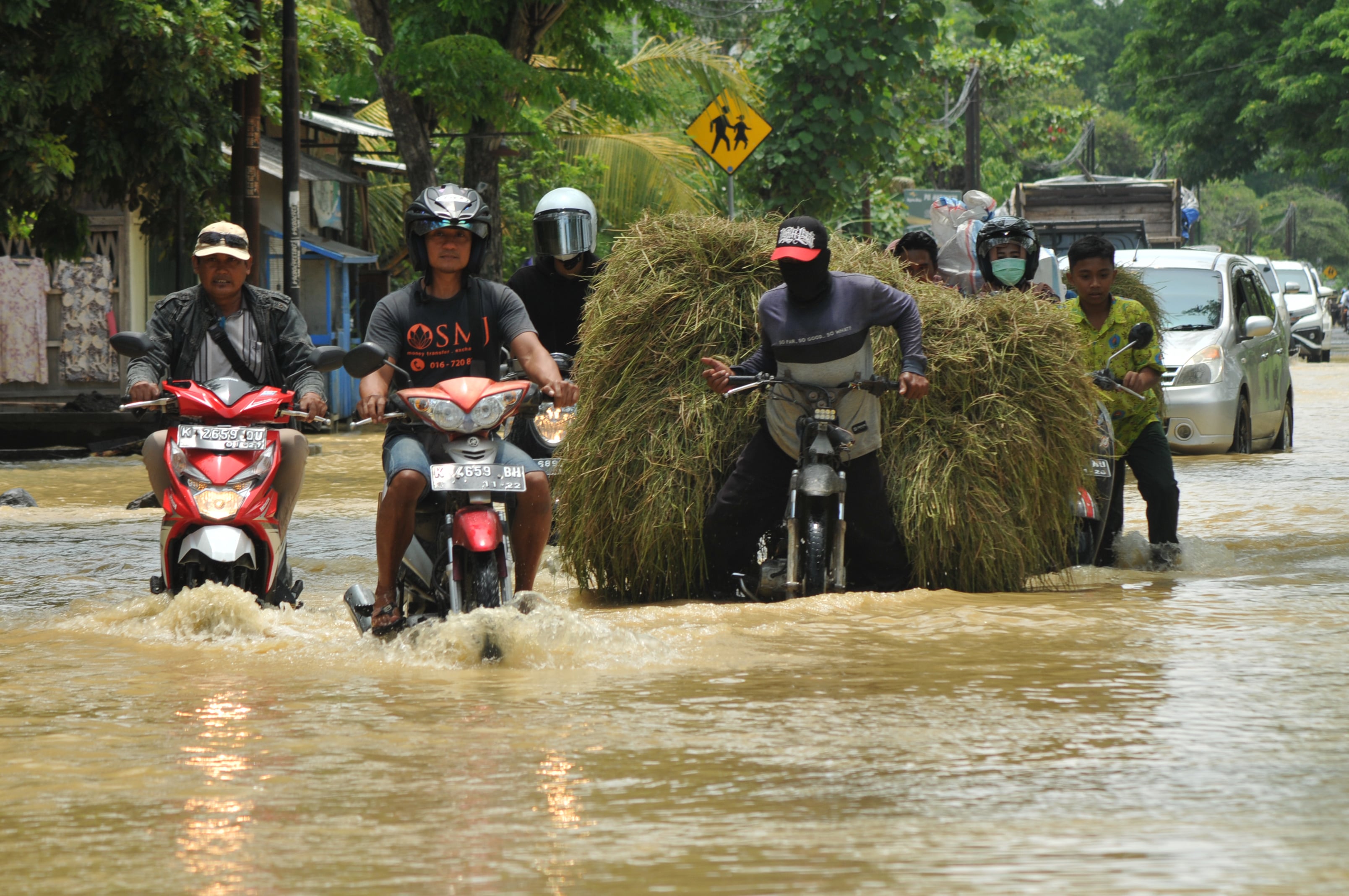  Warga melintasi jalan yang tergenang banjir di Desa Sembaturagung, Jakenan, Pati, Jawa Tengah, Sabtu (15/10/2022)