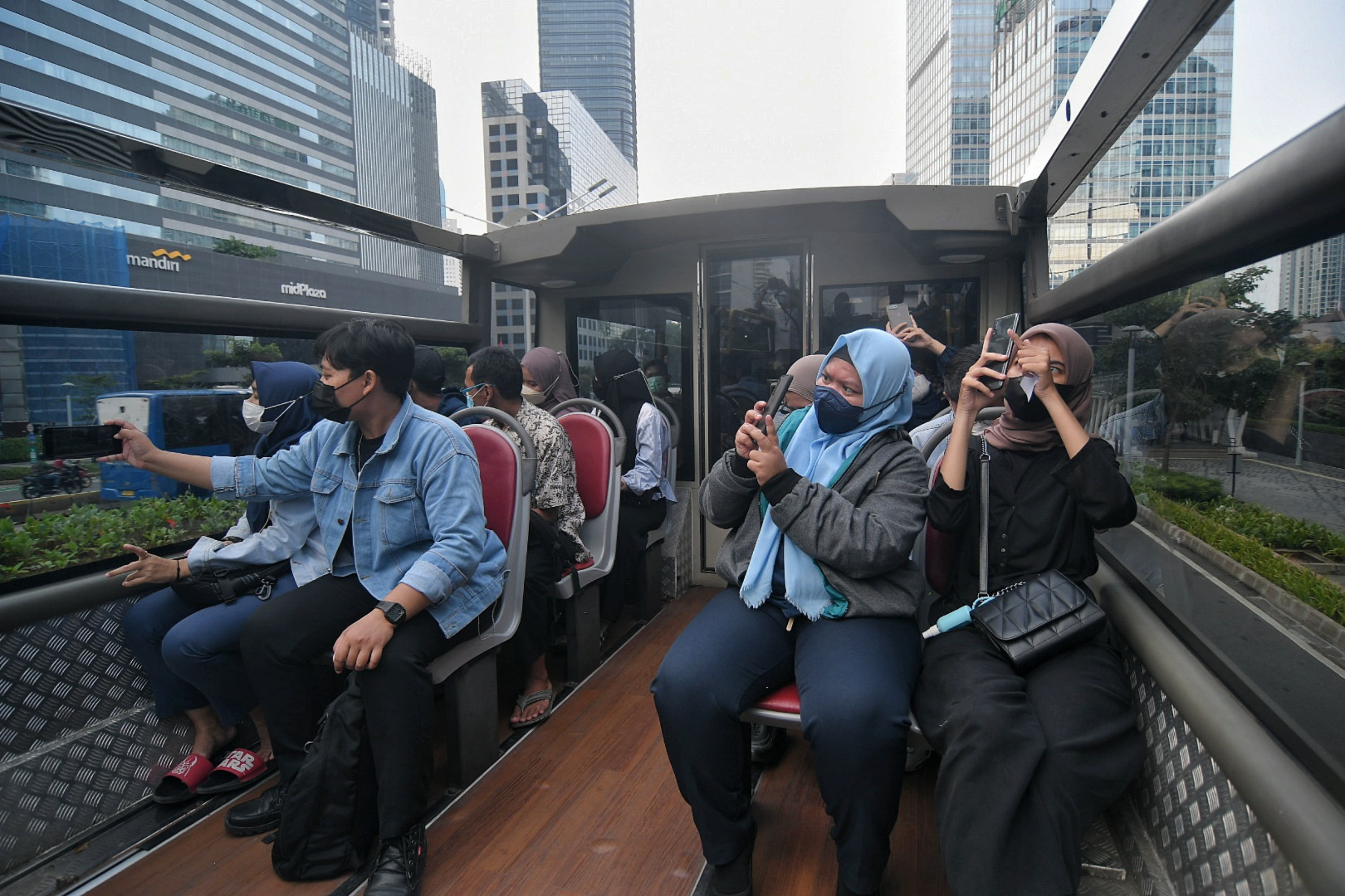 Warga menaiki bus wisata terbuka untuk menikmati suasana kota dari atas bus wisata di Jakarta