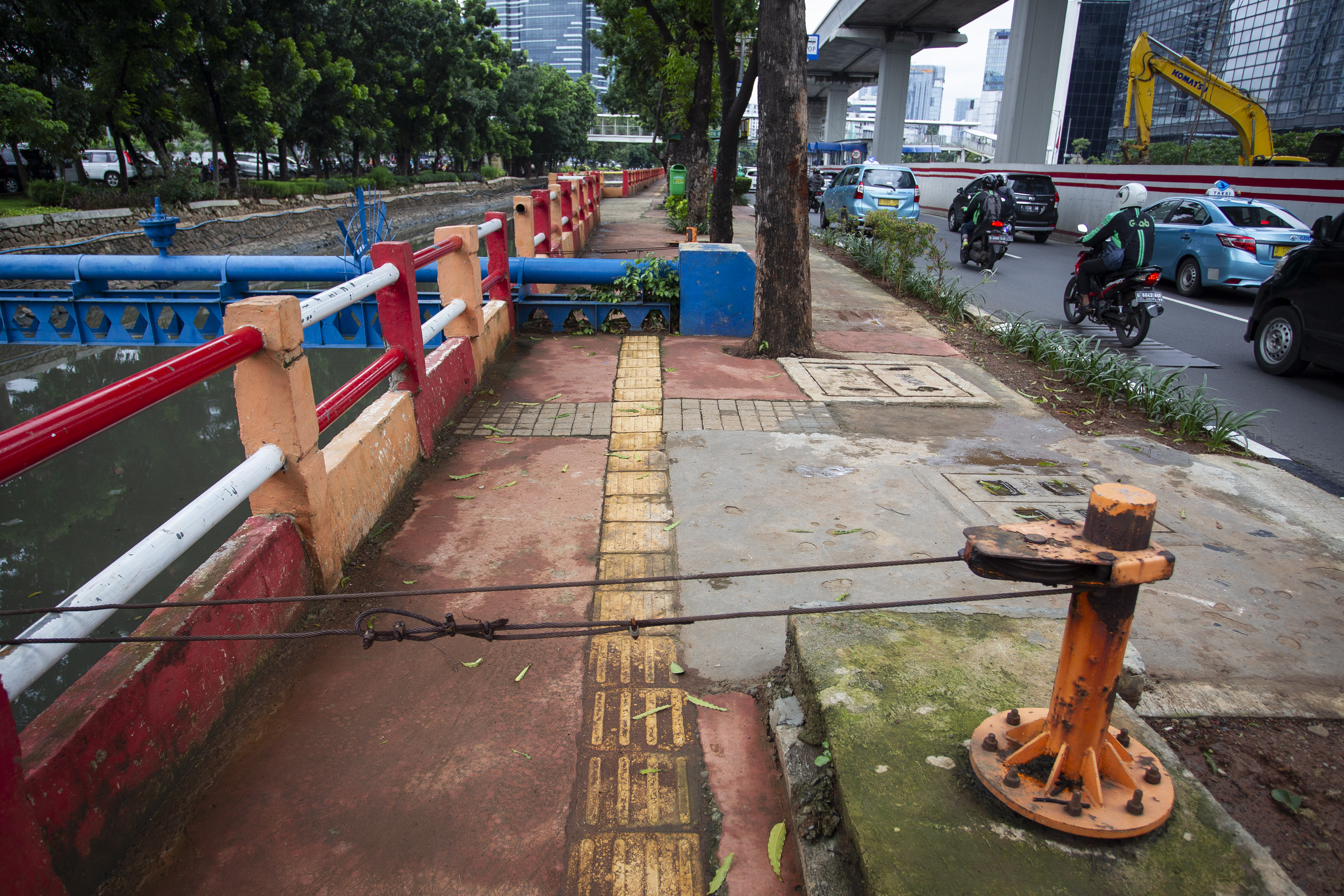 Jalur pemandu khusus disabilitas (guiding block) terhalang kawat dan instalasi pipa di trotoar kawasan Kuningan, Jakarta.