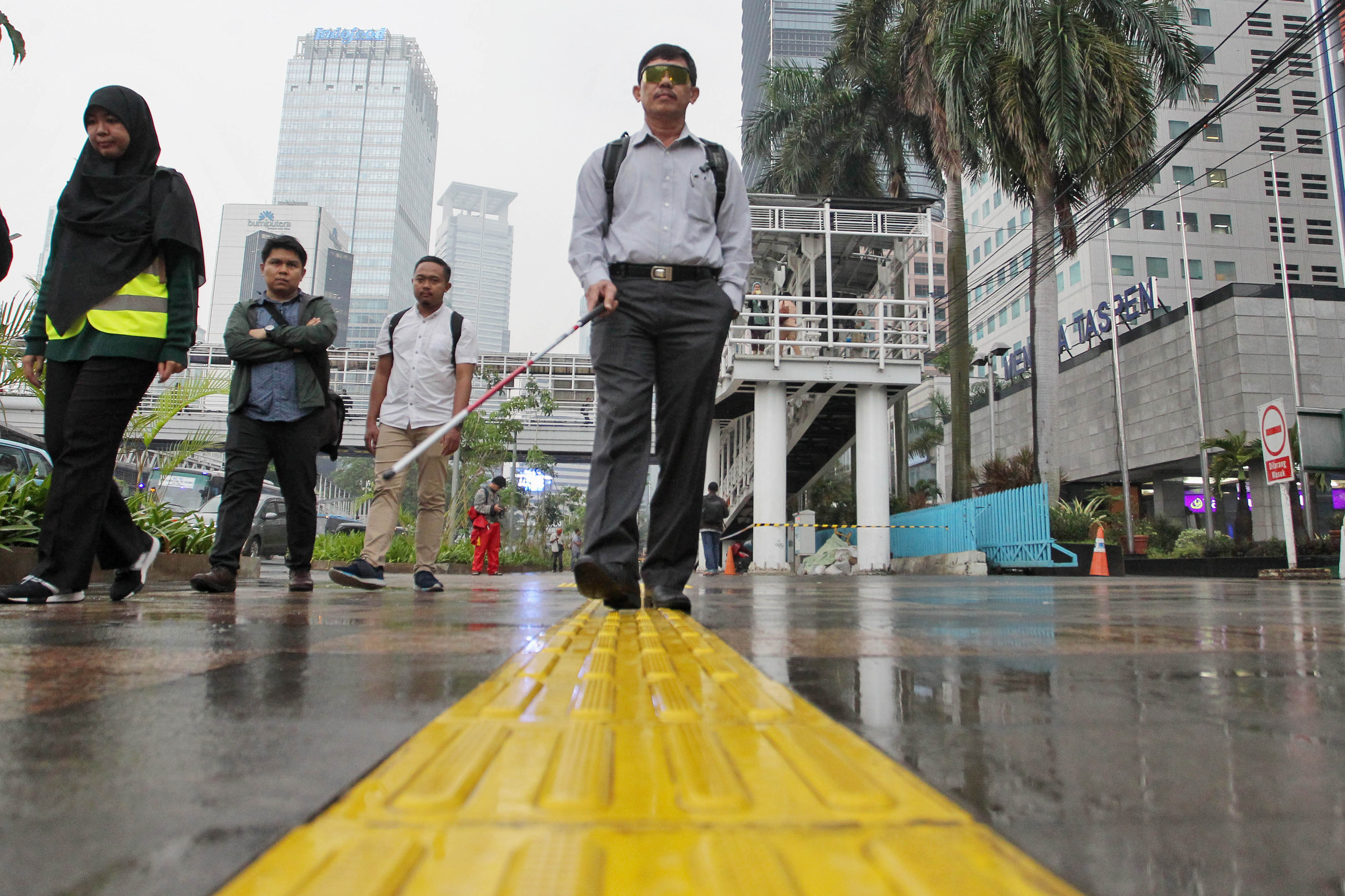 Pejalan kaki melakukan uji coba fasilitas umum ramah disabilitas di trotoar Dukuh Atas, Jalan Sudirman, Jakarta.