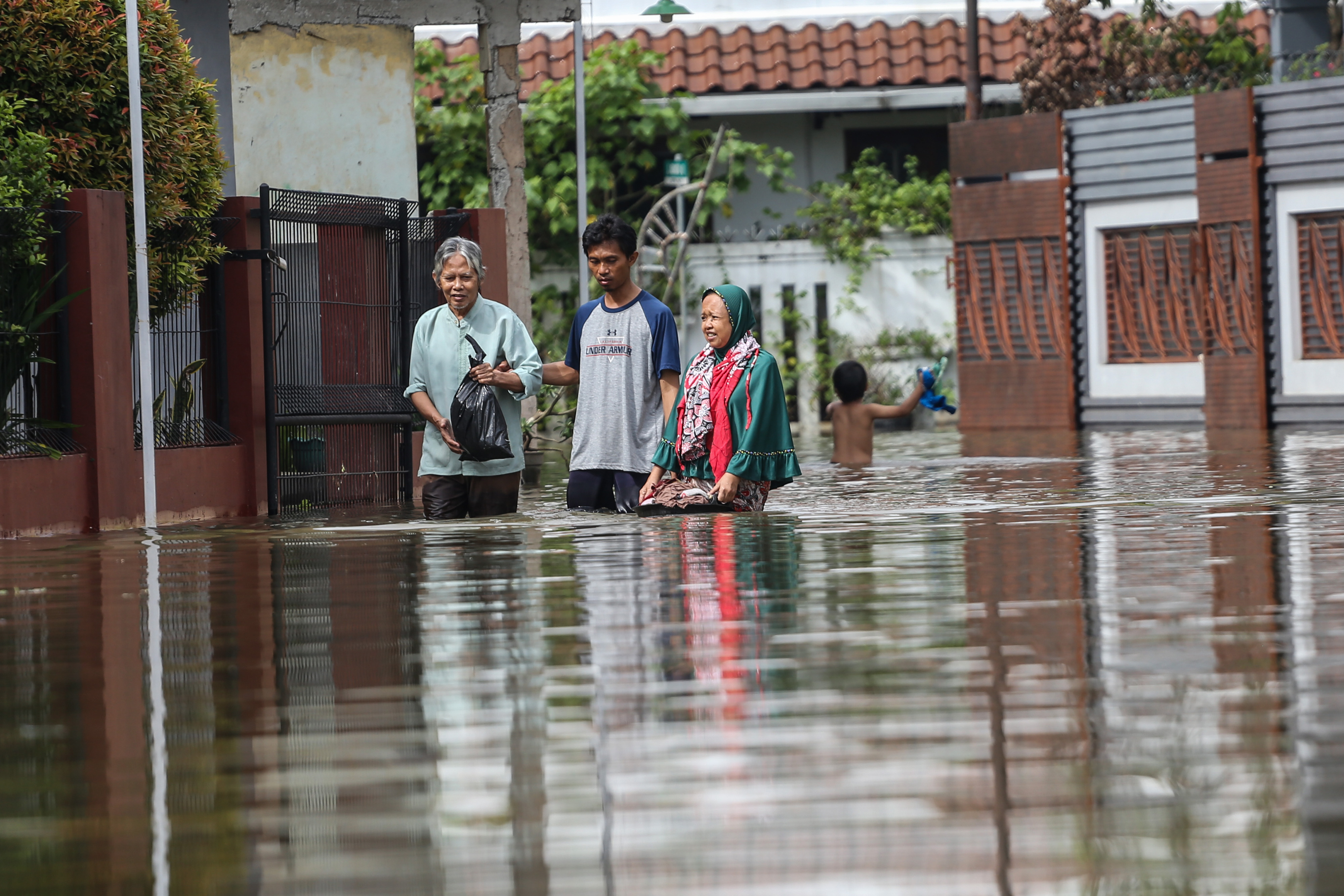 Sejumlah warga berjalan melintasi banjir di Perumahan Pondok Tirta Mandala, Depok